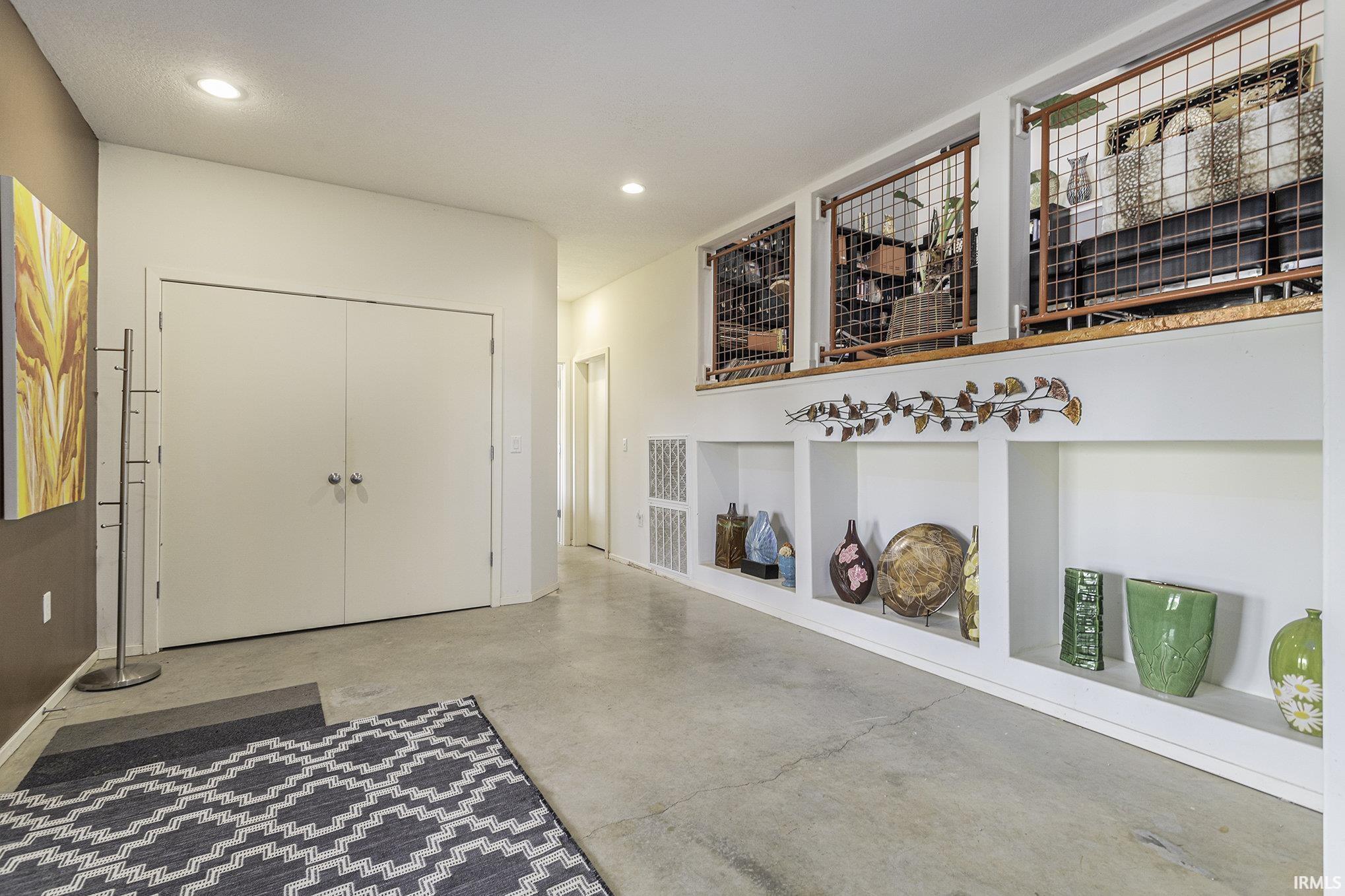 Expansive concrete flooring throughout, recessed lighting, built-in display niches, and a multi-level architectural feature with grid accents