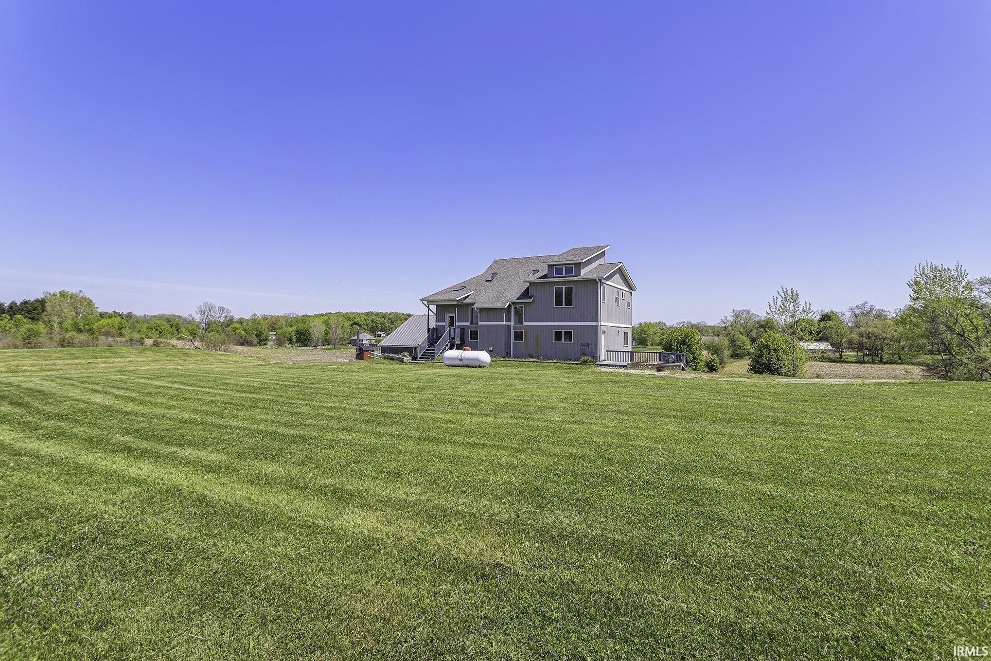 Expansive green lawn with a contemporary multi-story residence featuring gray siding and a gray shingle roof
