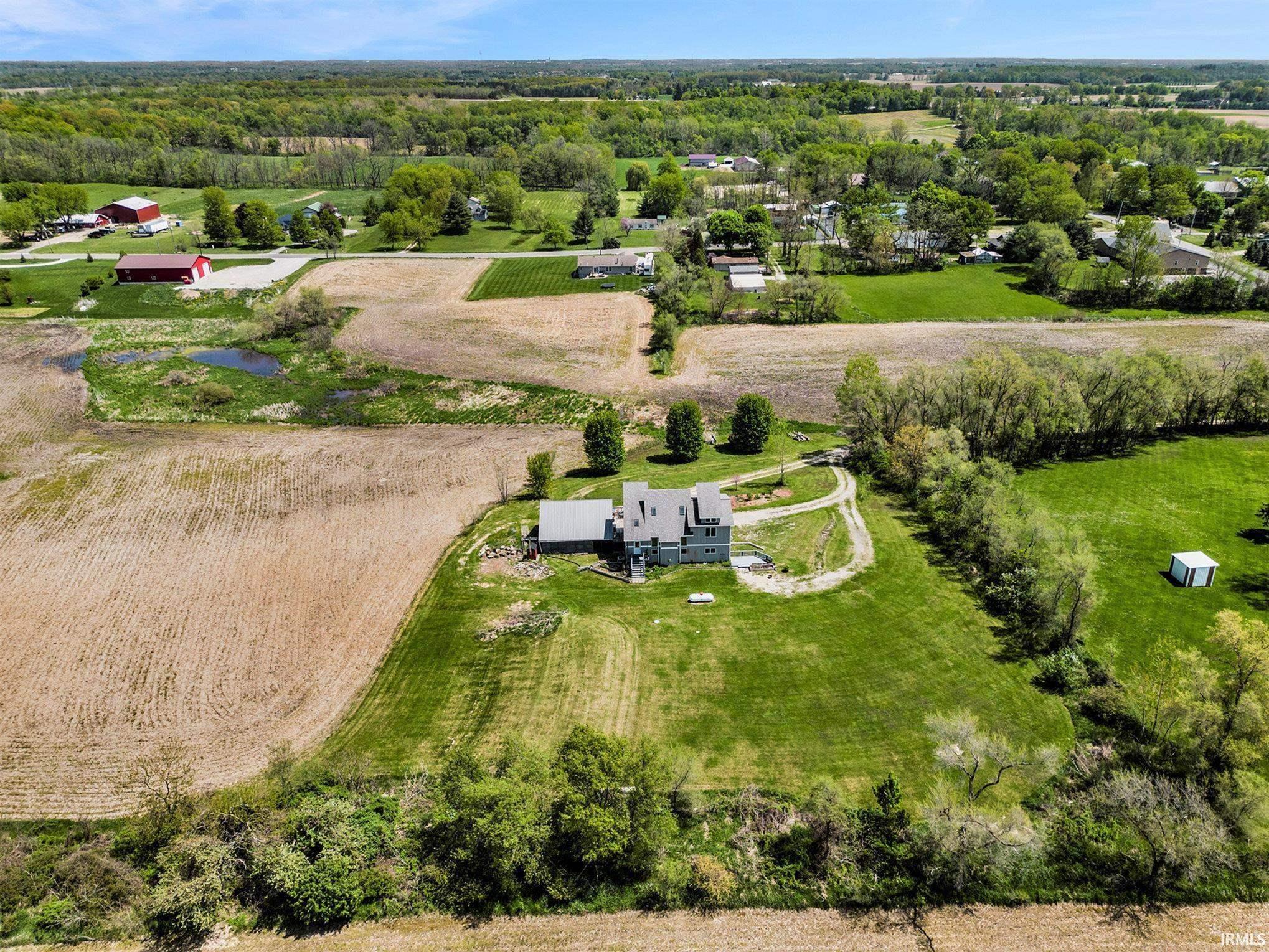 Expansive property featuring a multi-story residence with a gray exterior, surrounding green lawns, and a private driveway