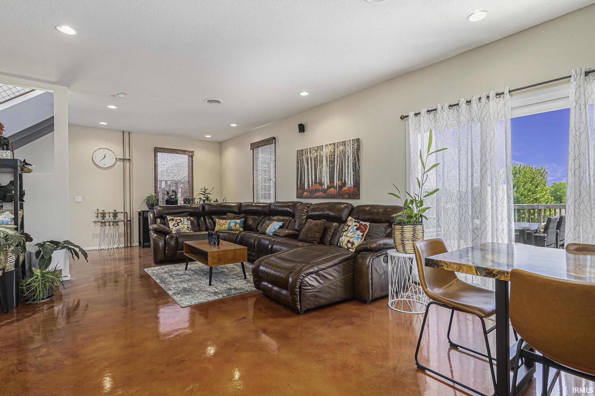 Spacious living area featuring polished concrete flooring, recessed lighting, and a large sliding glass door