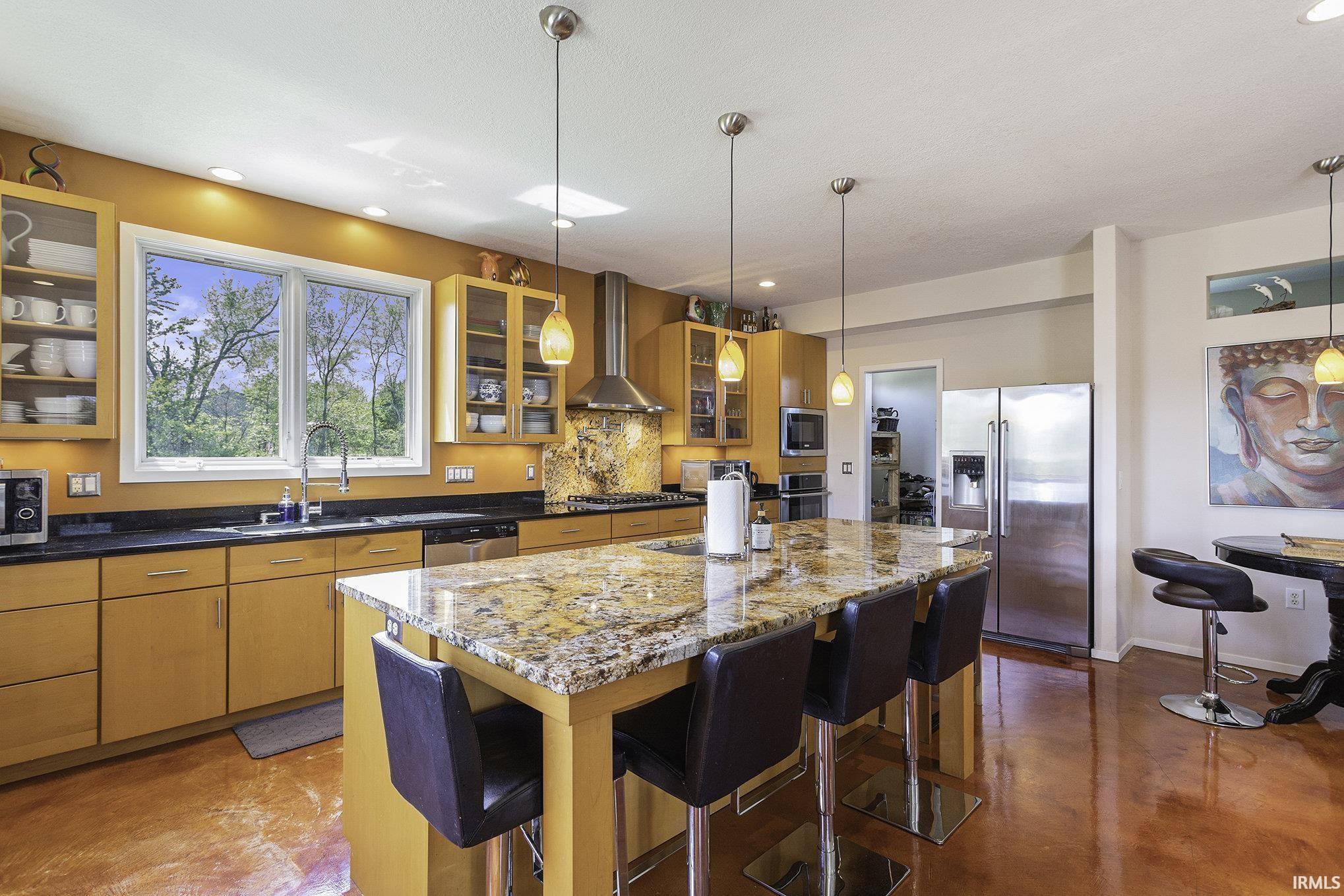 Gourmet kitchen featuring a large granite island with seating, stainless steel appliances, wood-finish cabinetry, and a skylight for natural illumination