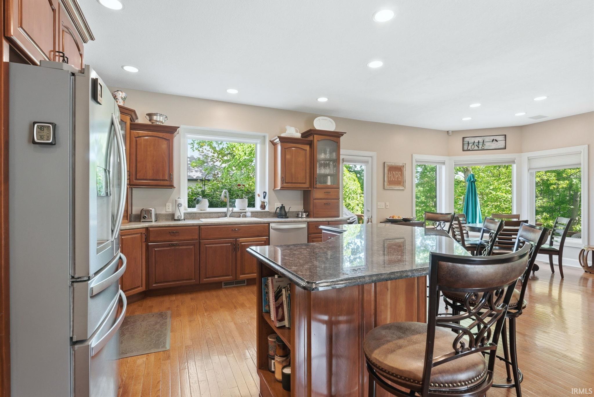 Open-concept kitchen featuring wood-finish flooring, recessed lighting, and an expansive island with a stone countertop