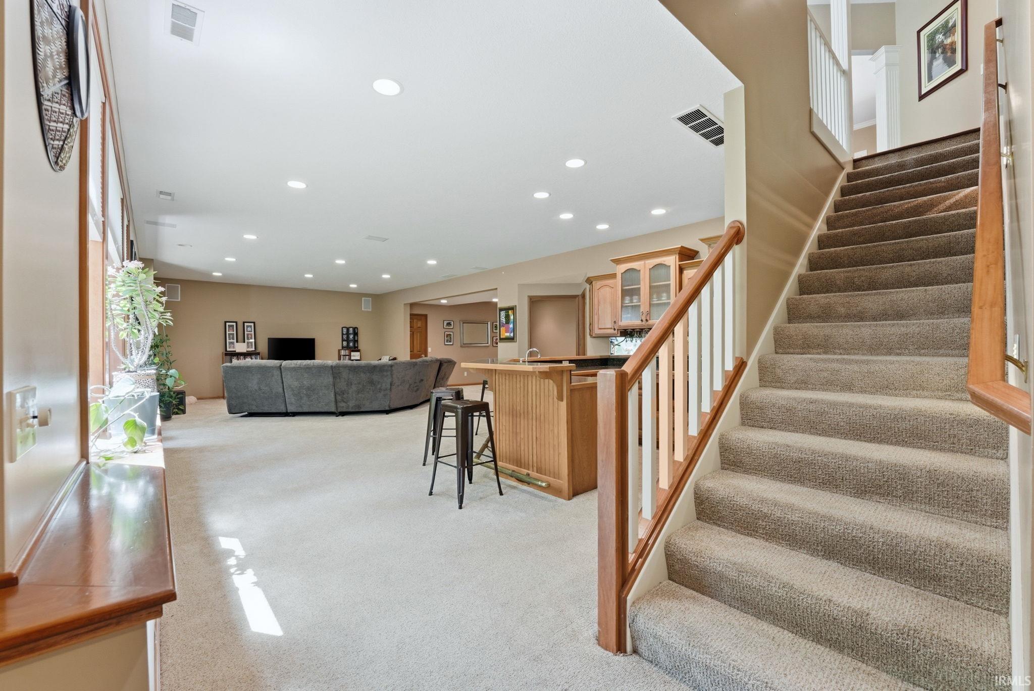 Carpeted staircase with wood handrail and white balusters