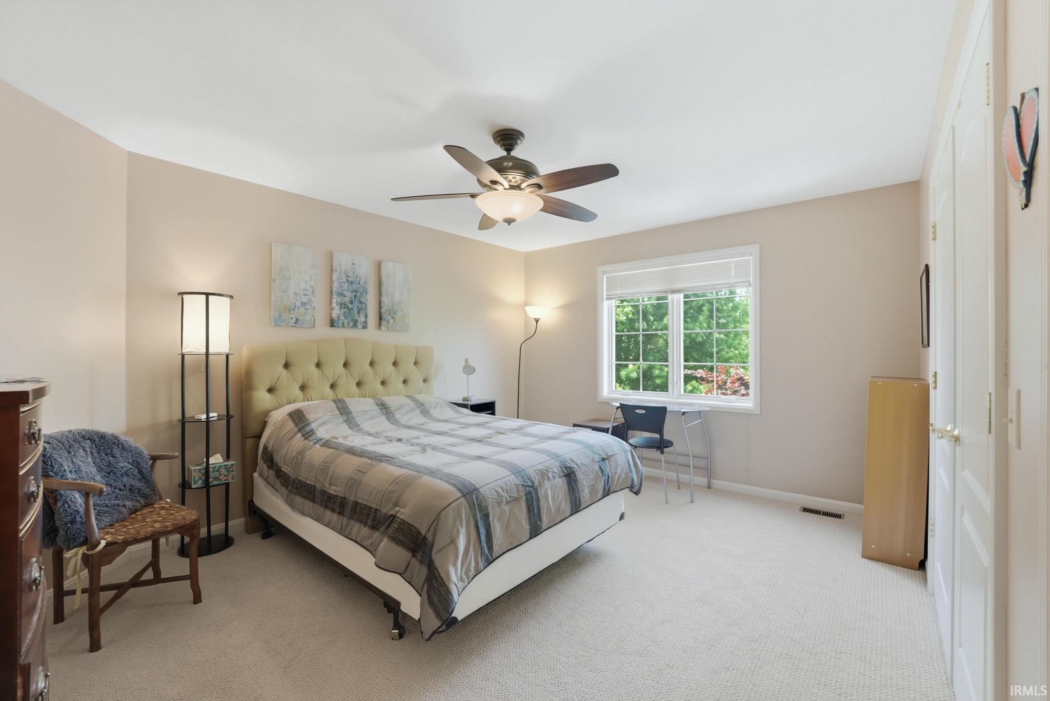 Carpeted room featuring a ceiling fan with integrated lighting, a window with white trim, and a pair of white paneled doors