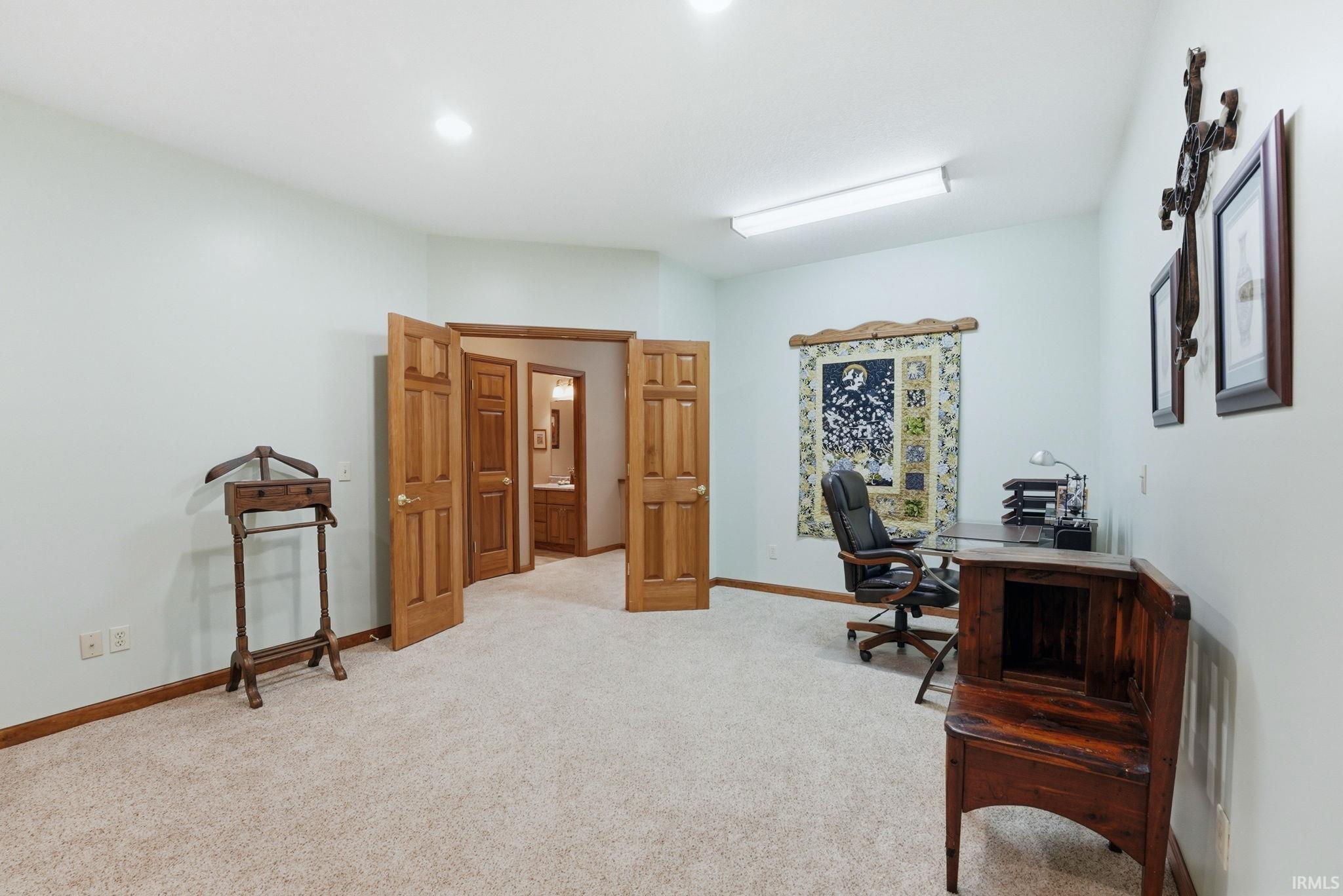 Spacious room featuring light-colored carpeting, light blue walls, and natural wood trim and doors