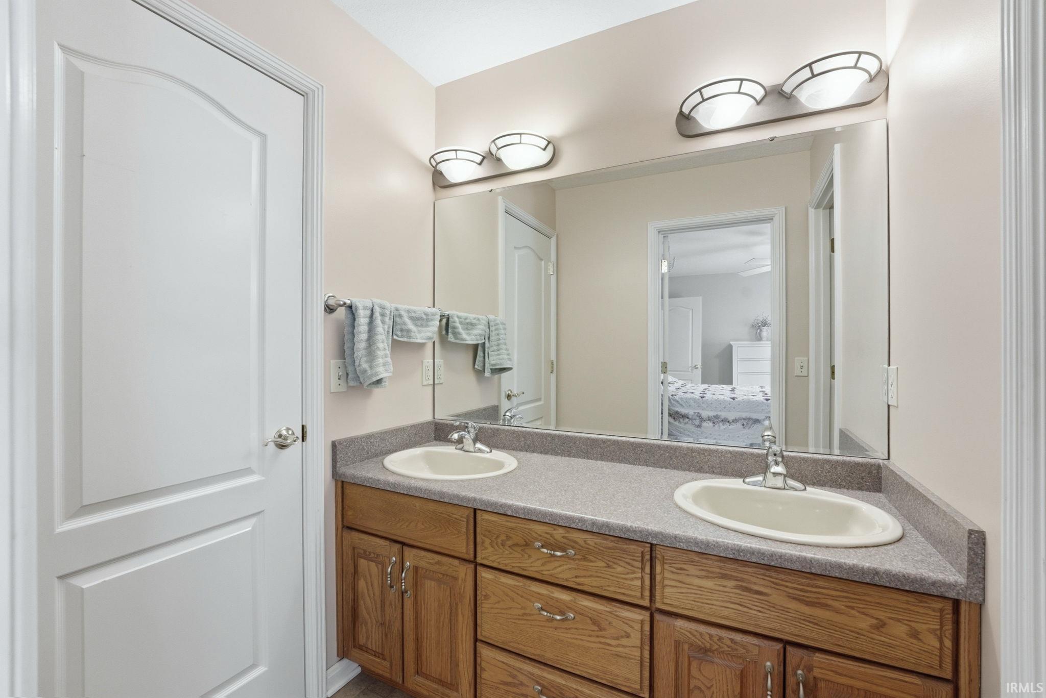 Dual vanity with wood-finish cabinetry and a neutral countertop