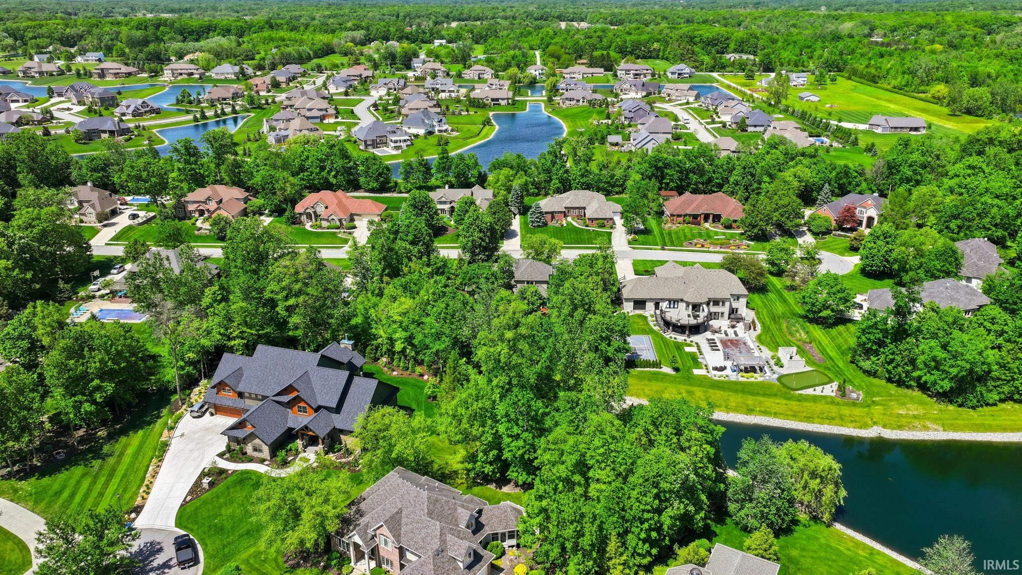 Lush green landscape featuring a residential community with multiple homes, a network of interconnected ponds, and abundant mature trees