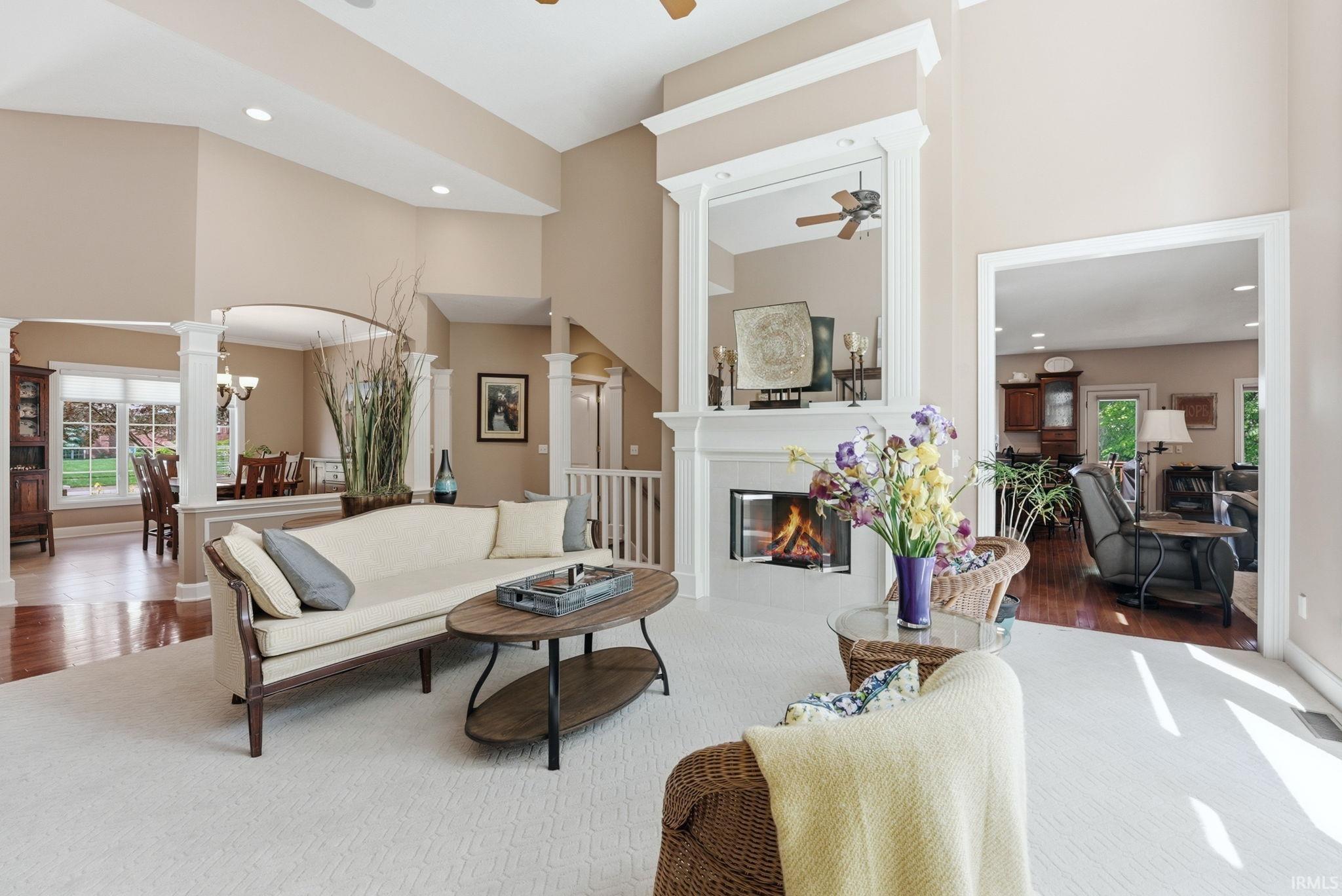 Spacious living area featuring a fireplace with a white mantel, high ceilings, and recessed lighting