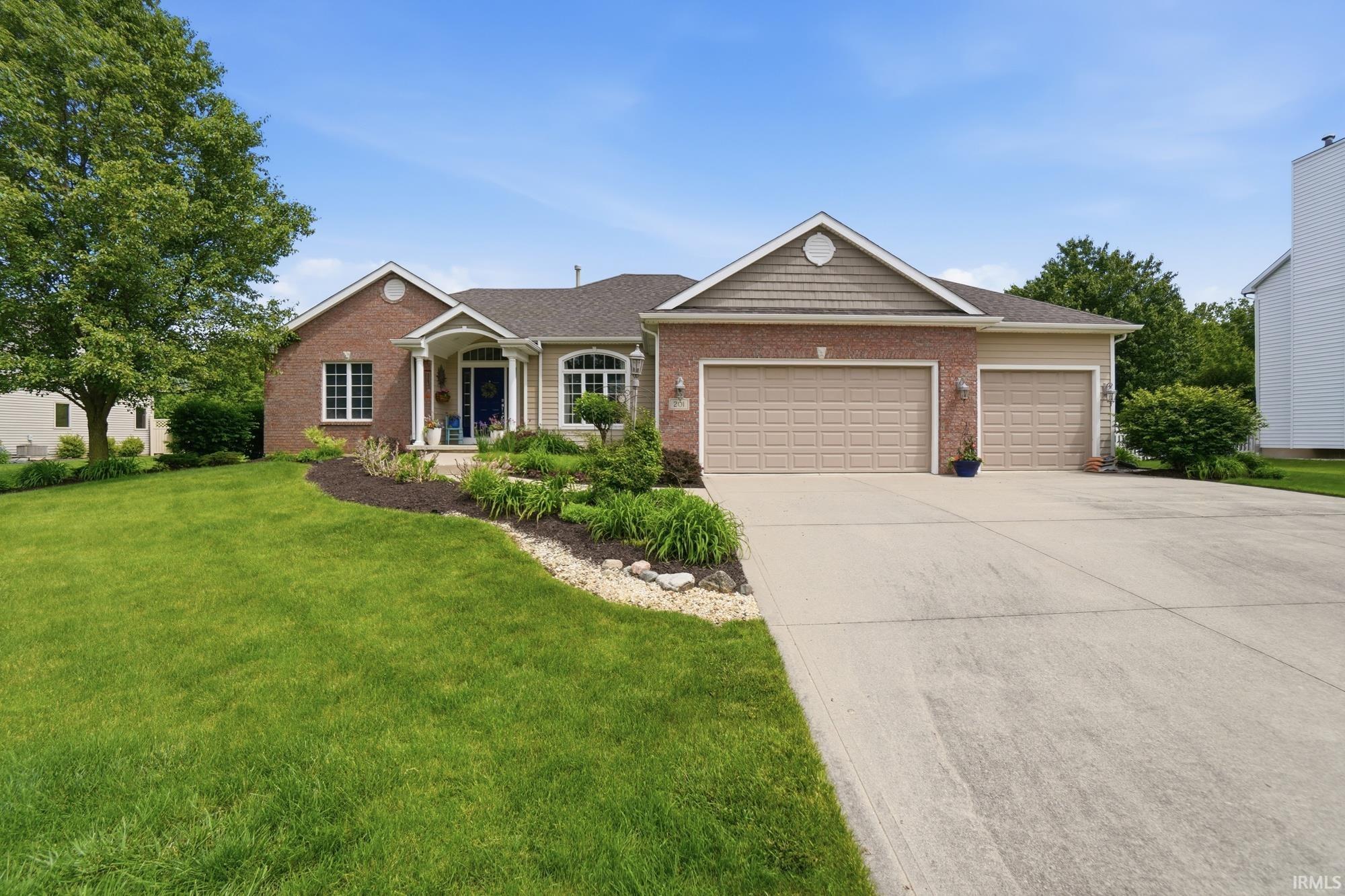 Brick and siding exterior featuring a three-car garage and a concrete driveway