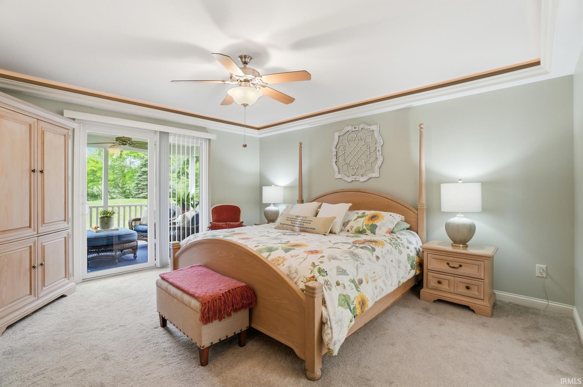 Carpeted bedroom with a tray ceiling and ceiling fan