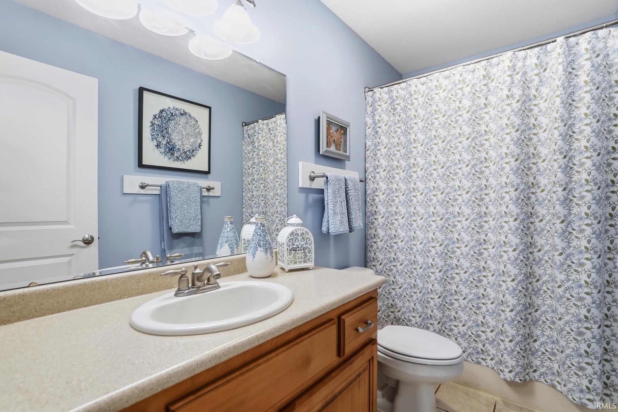 Bathroom featuring a single-basin vanity with a light-toned countertop, wood-finish cabinetry, and a chrome faucet