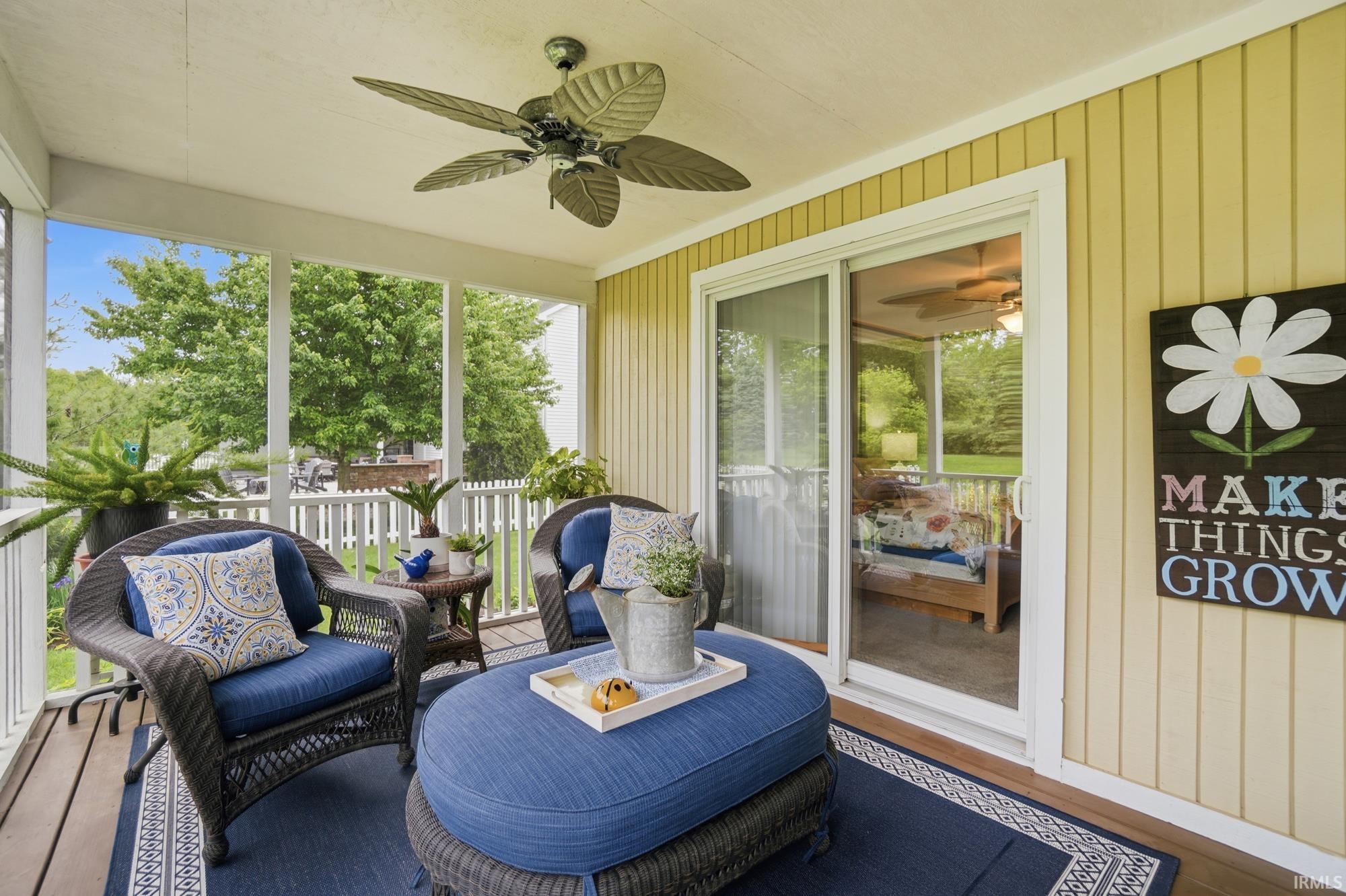 Screened porch featuring a ceiling fan, sliding glass door, and yellow vertical siding