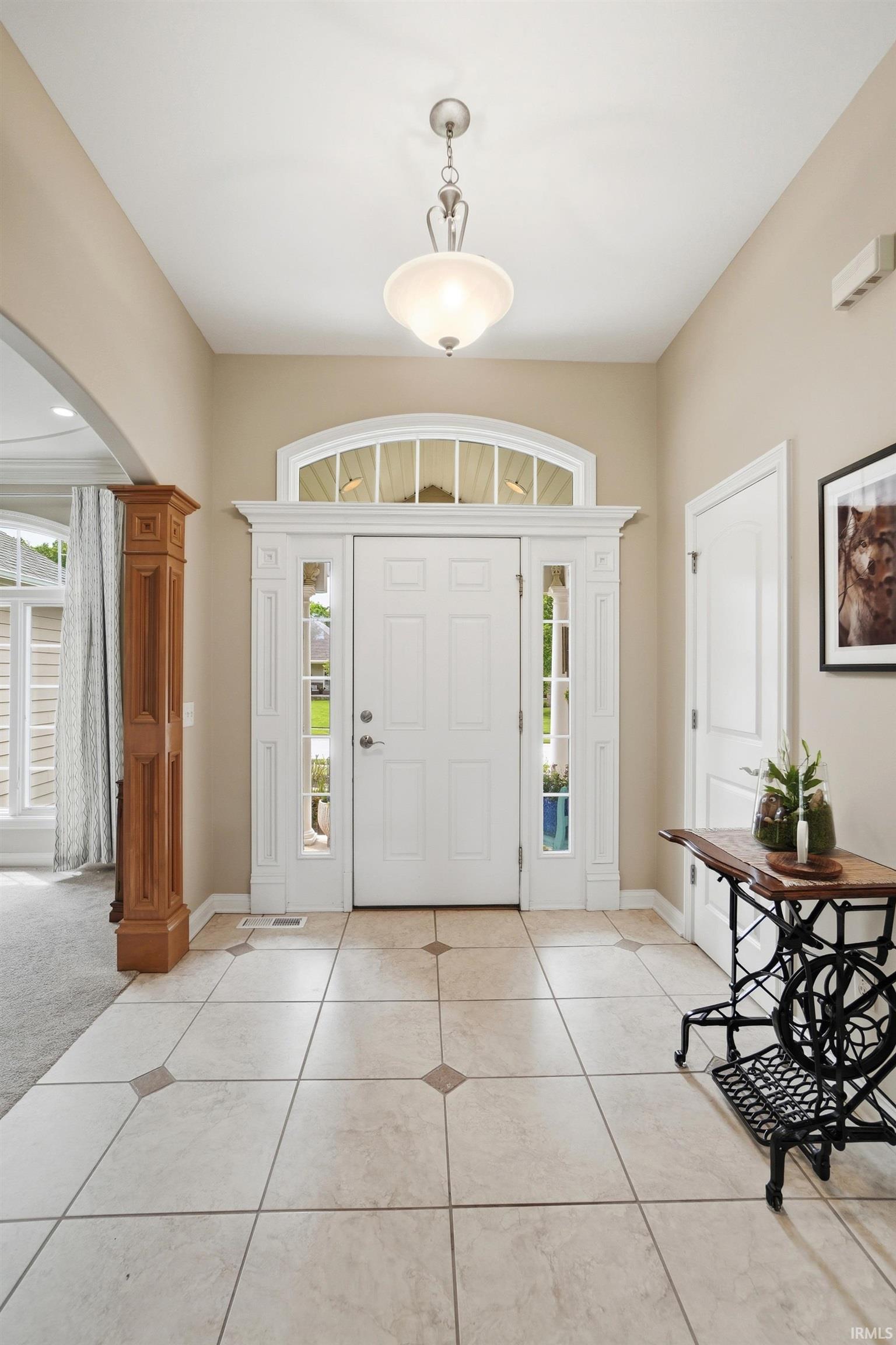 Welcoming entryway featuring a paneled front door with sidelights, an arched transom window, and decorative trim