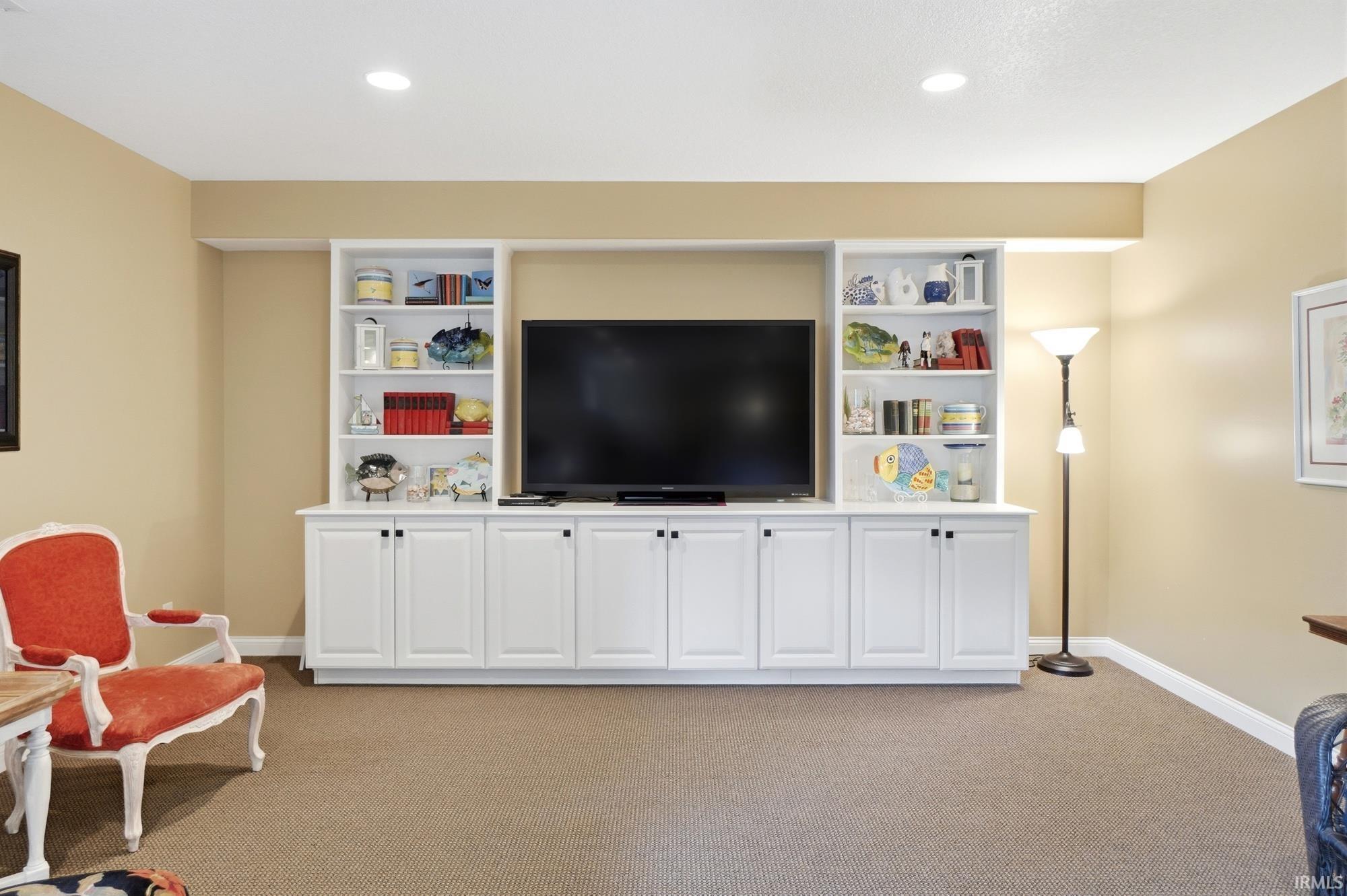Built-in media center with white cabinetry, open shelving, and black hardware