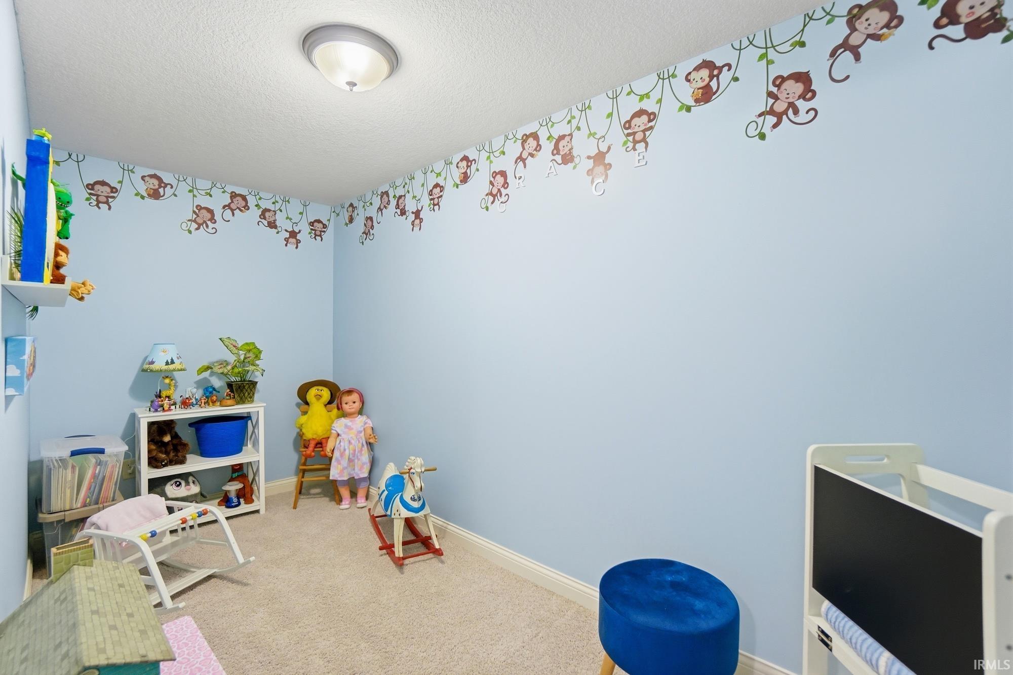 Room featuring light blue walls with decorative border, white baseboards, and neutral carpet flooring