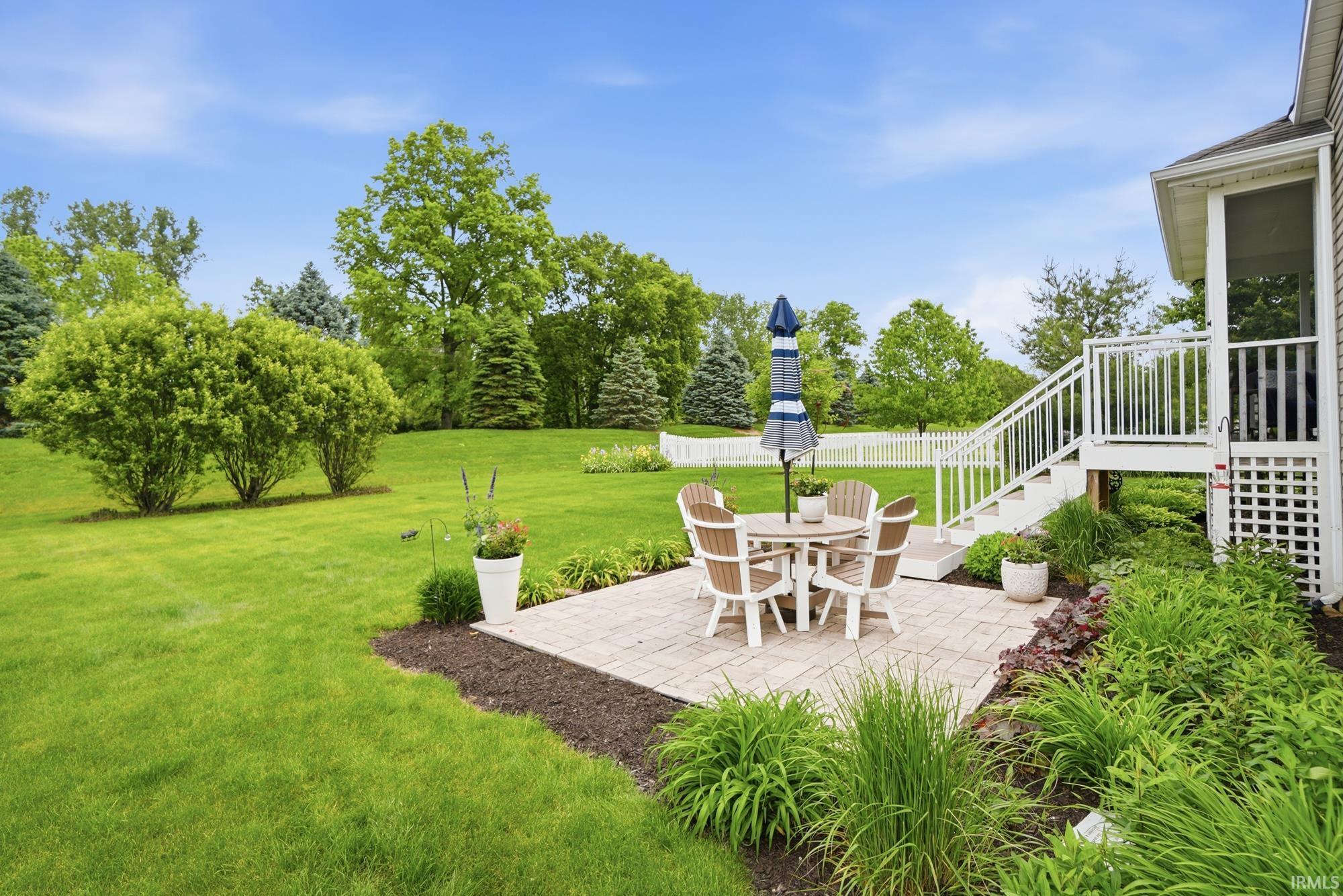 Expansive green lawn featuring a paver patio area with direct access to a white screened porch