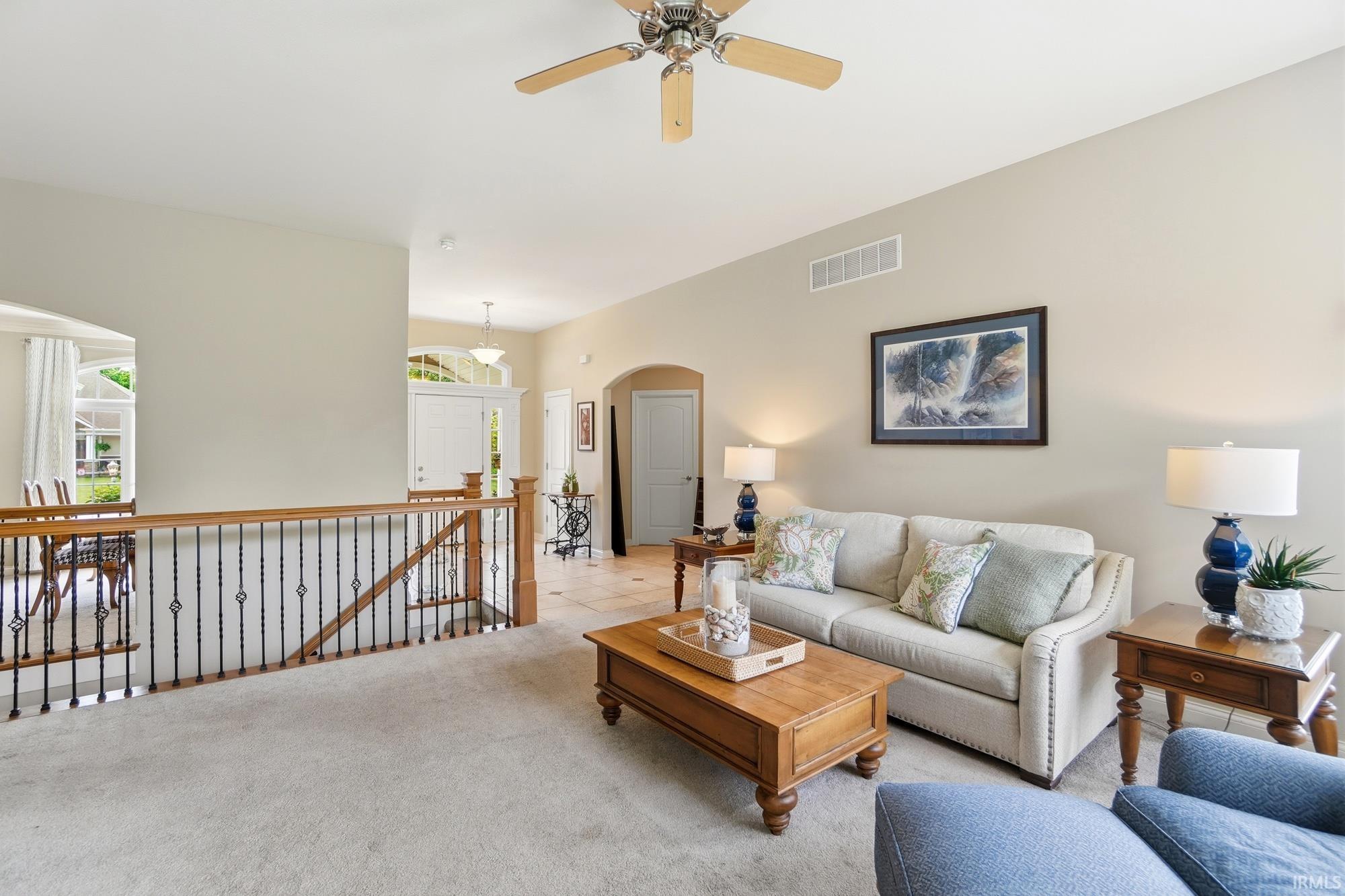 Open concept living area featuring light neutral wall tones and textured carpeting