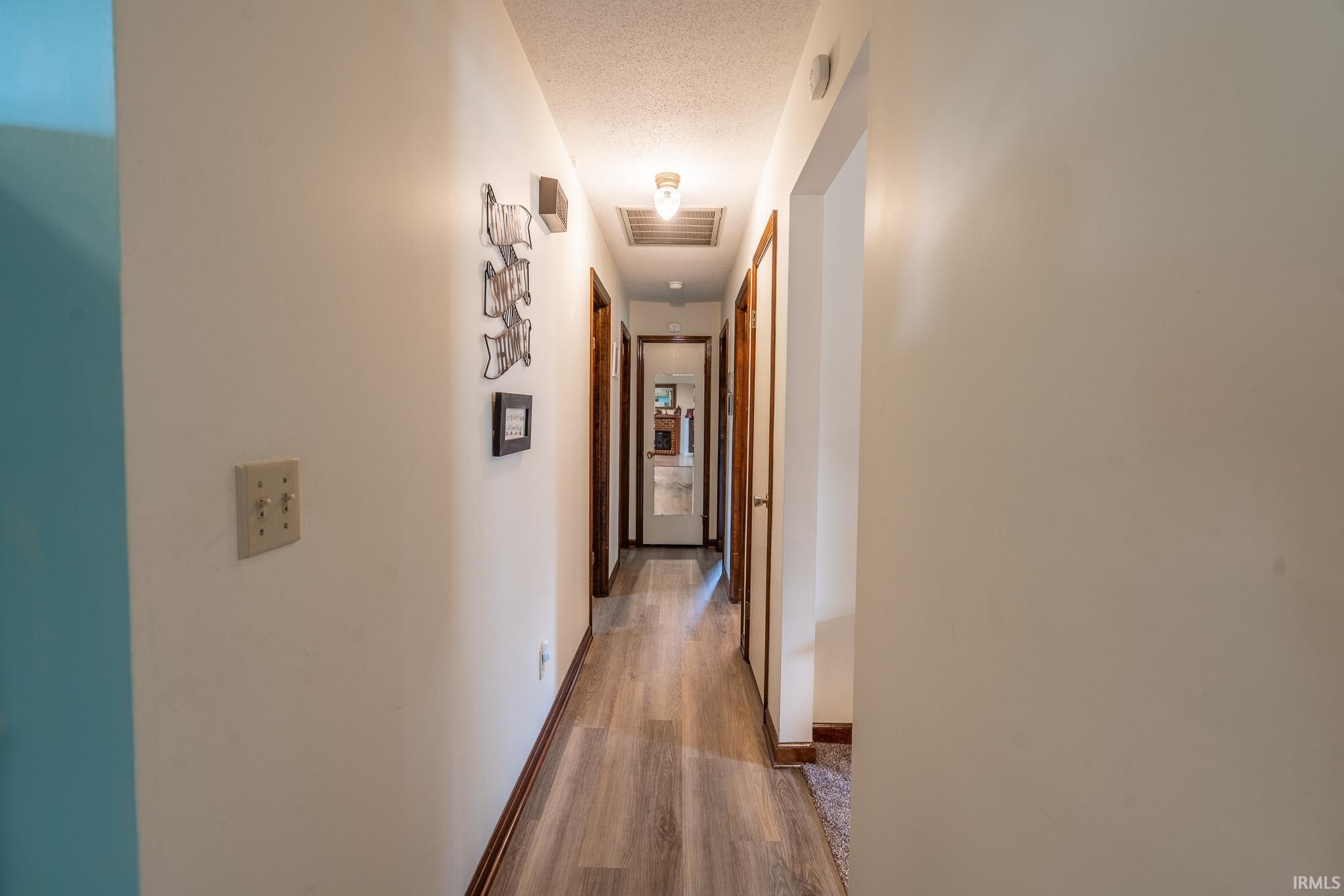 Hallway featuring wood-finish flooring, white walls, and wood-paneled doors