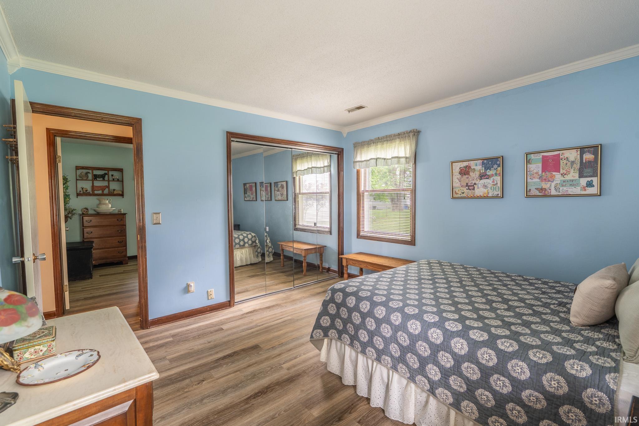 Interior room featuring wood-finish flooring, two windows with wood trim, and crown molding
