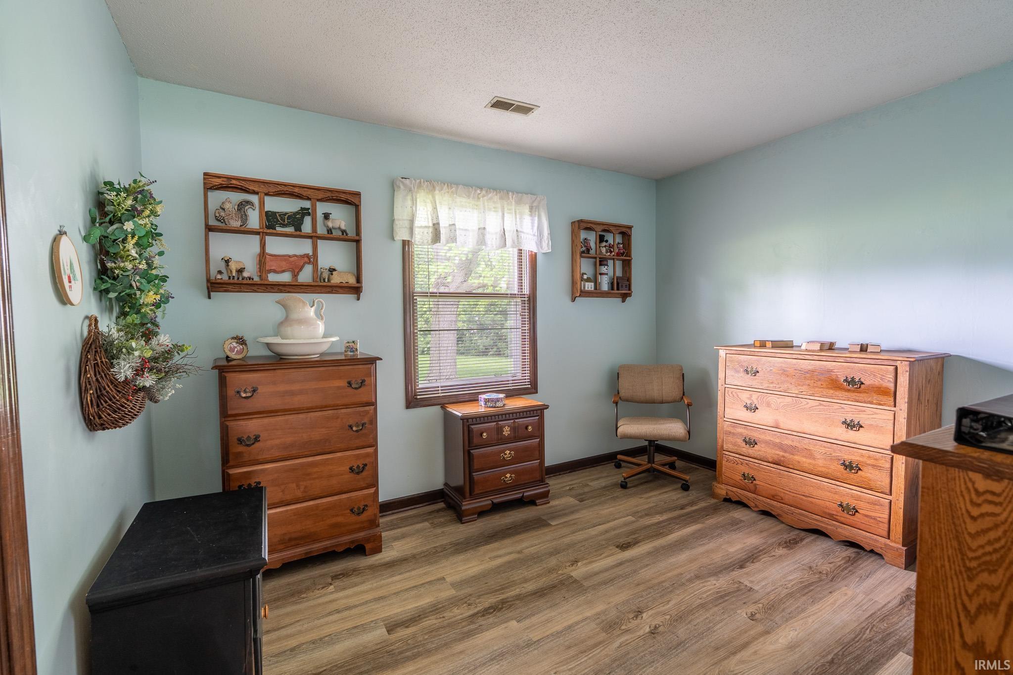 Interior room featuring wood-finish flooring, light blue wall paint, and a window with exterior views