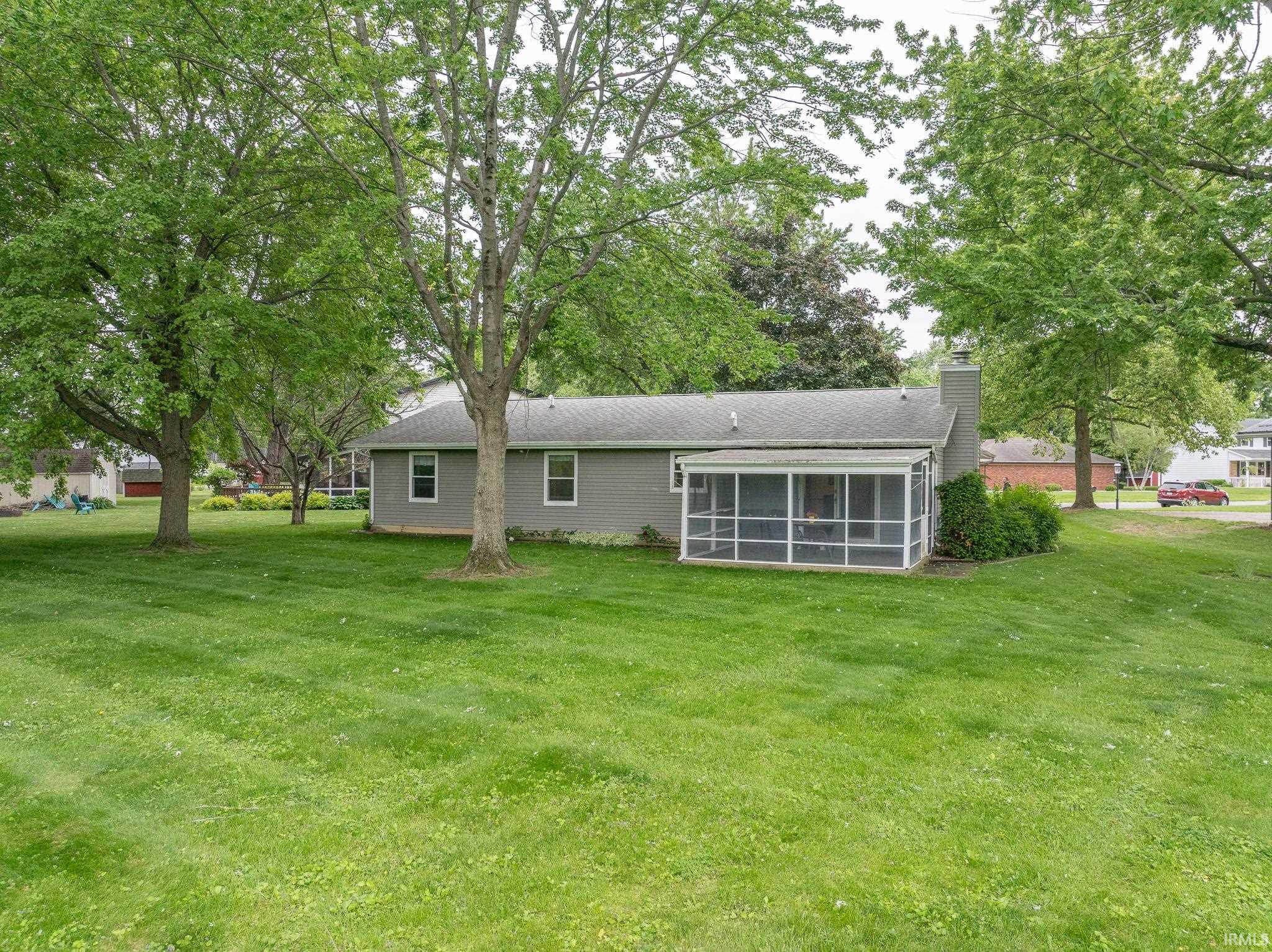 Expansive green lawn surrounds a grey-sided home featuring a screened porch addition