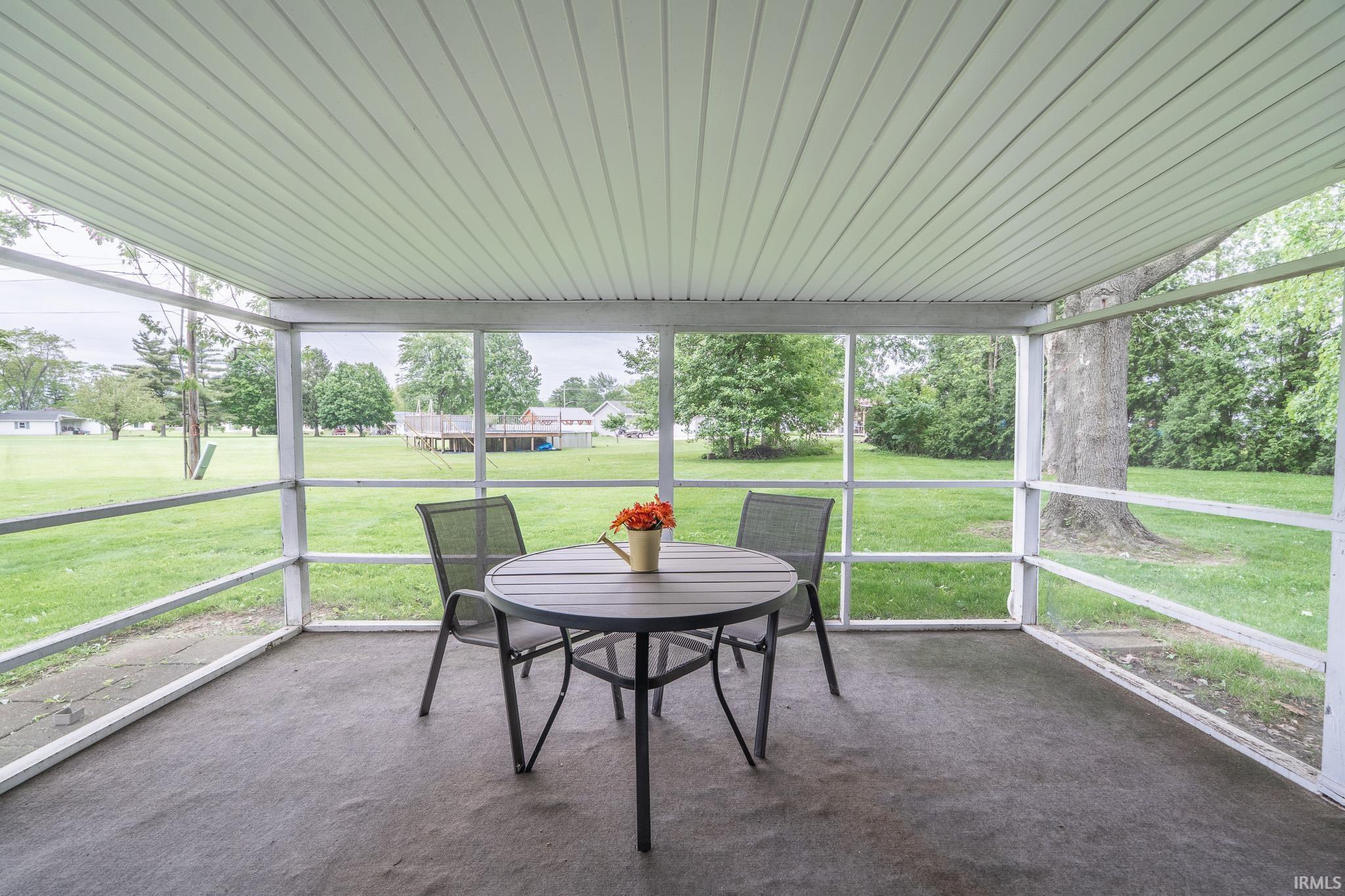Screened porch featuring a white slatted ceiling and concrete flooring