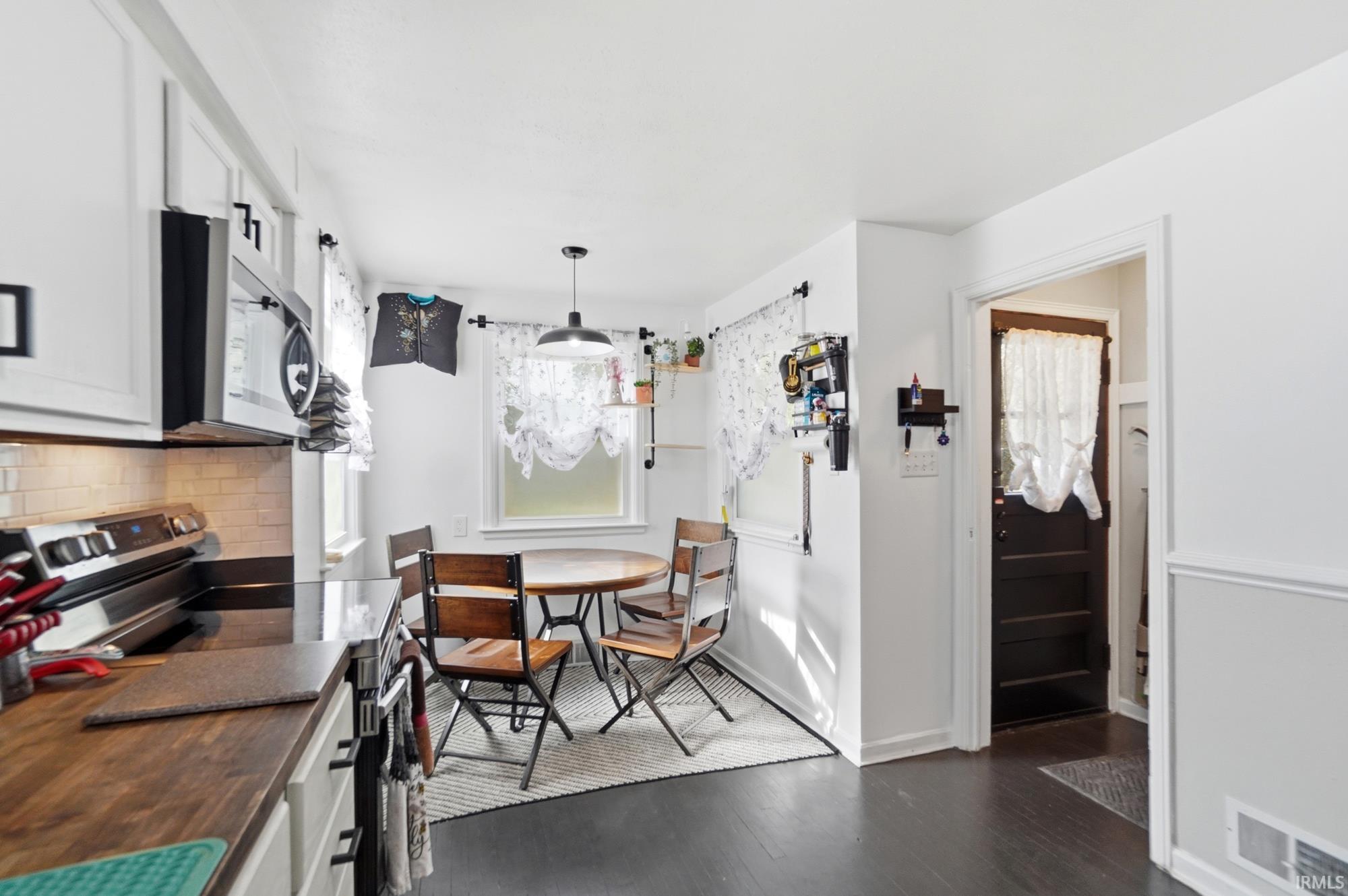 Kitchen featuring a stainless steel range, built-in microwave, white shaker-style cabinetry with matte black hardware, and wood-finish countertops