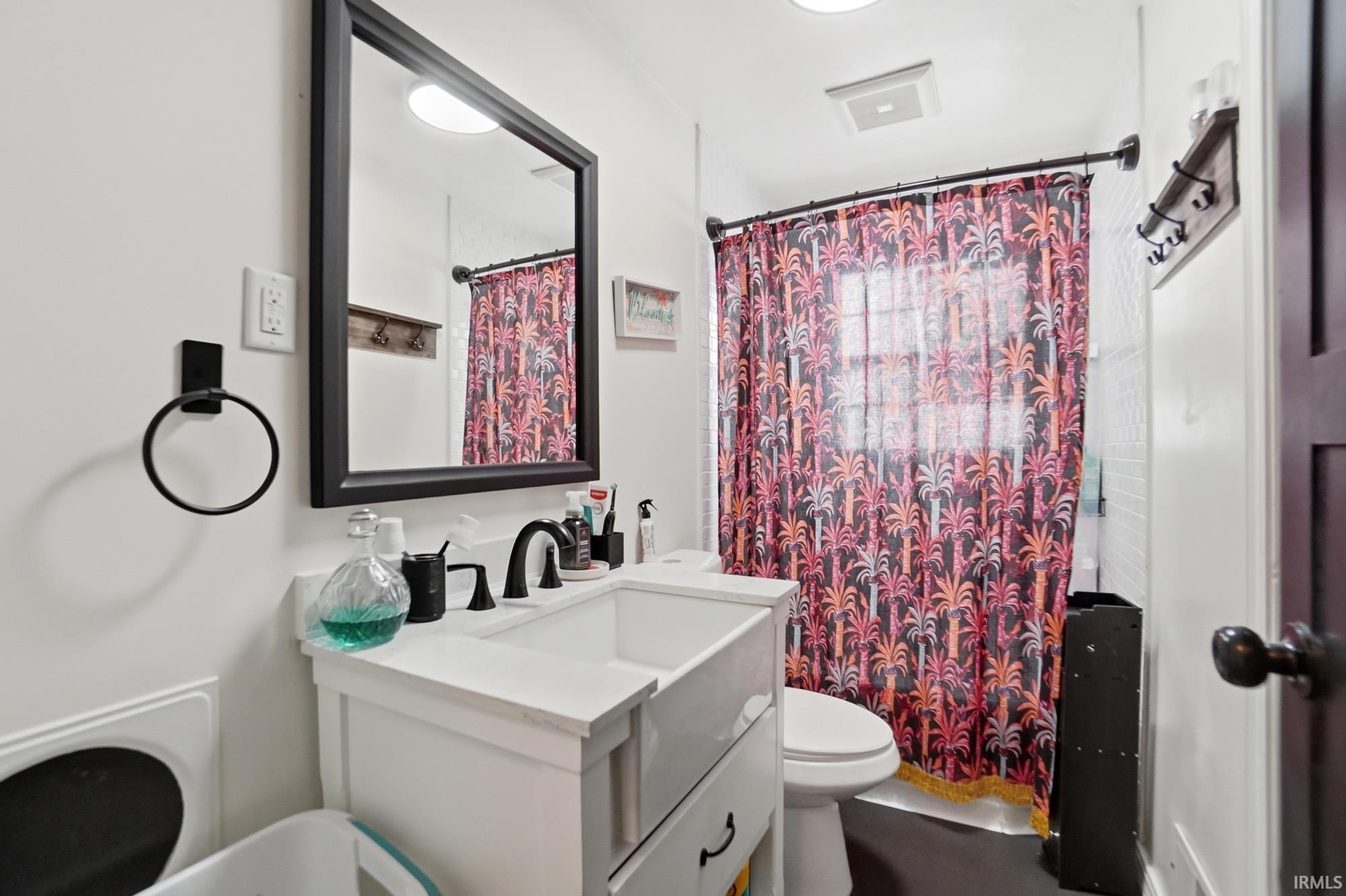 Bathroom featuring a white vanity with a single basin sink, matte black faucet, and a framed mirror