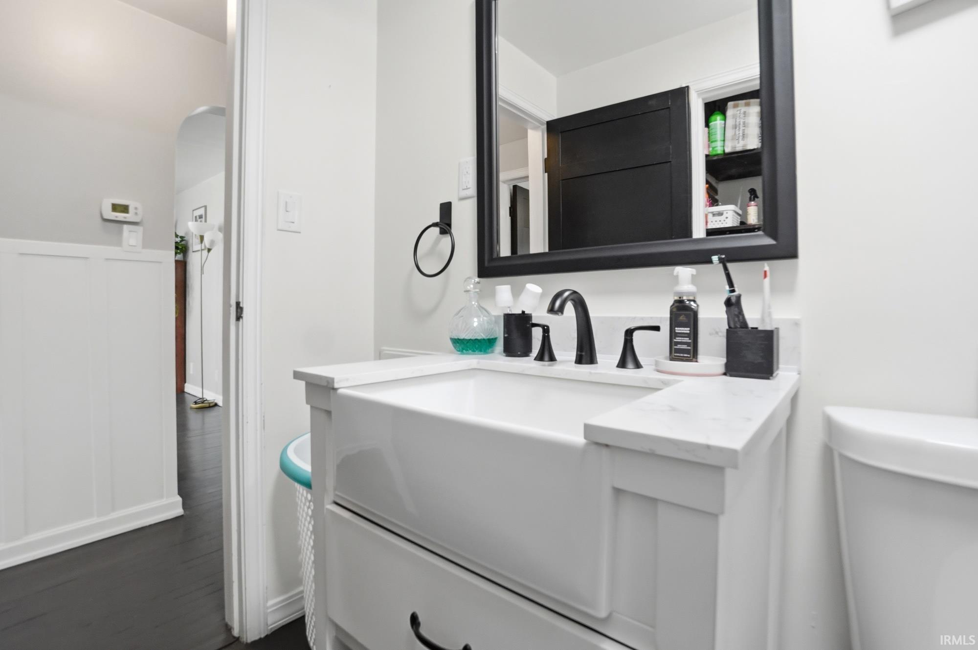 Bathroom vanity featuring a farmhouse-style sink, white countertop, and matte black fixtures