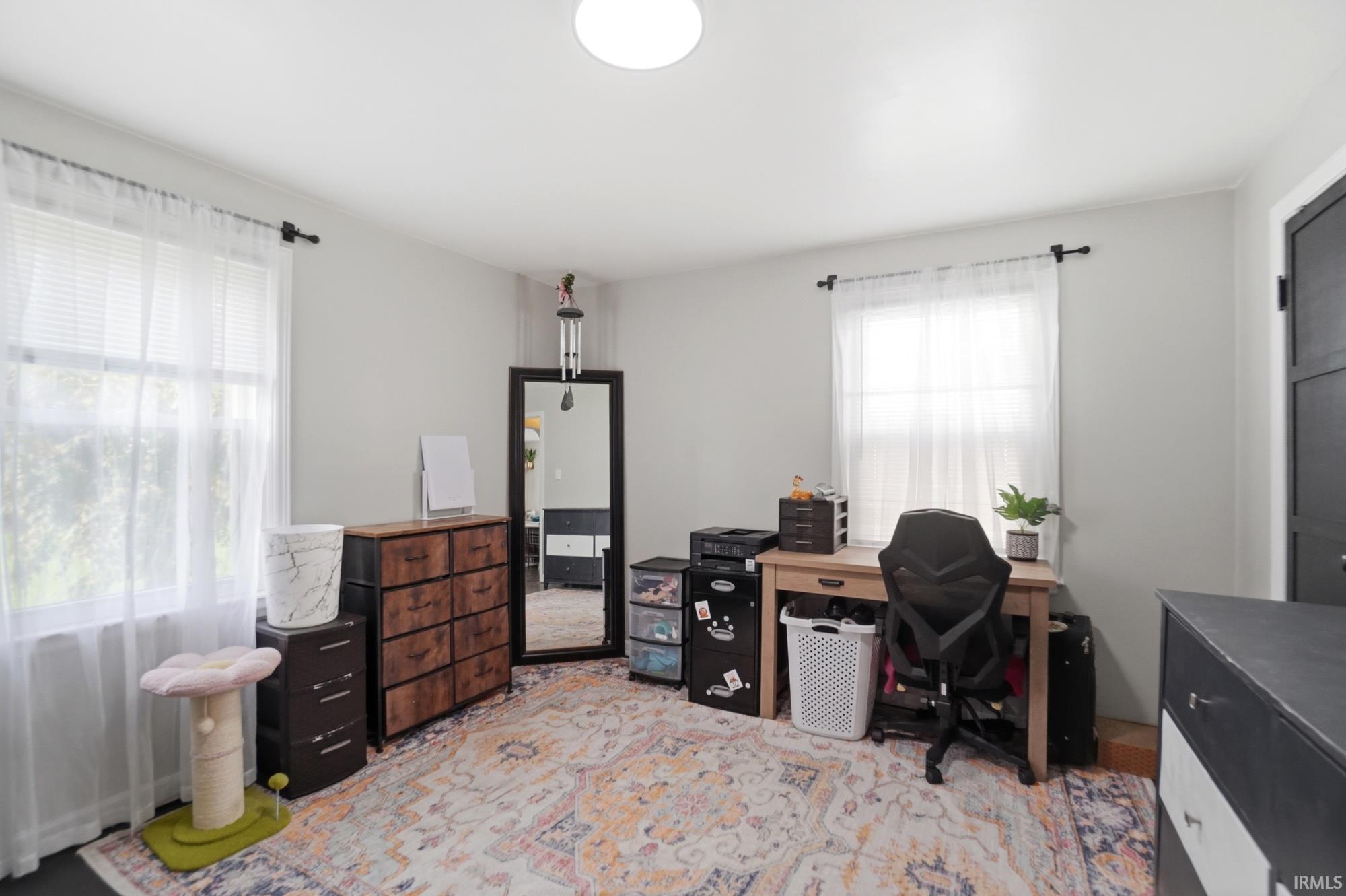 Room featuring two windows, light gray walls, a ceiling-mounted light fixture, and dark flooring