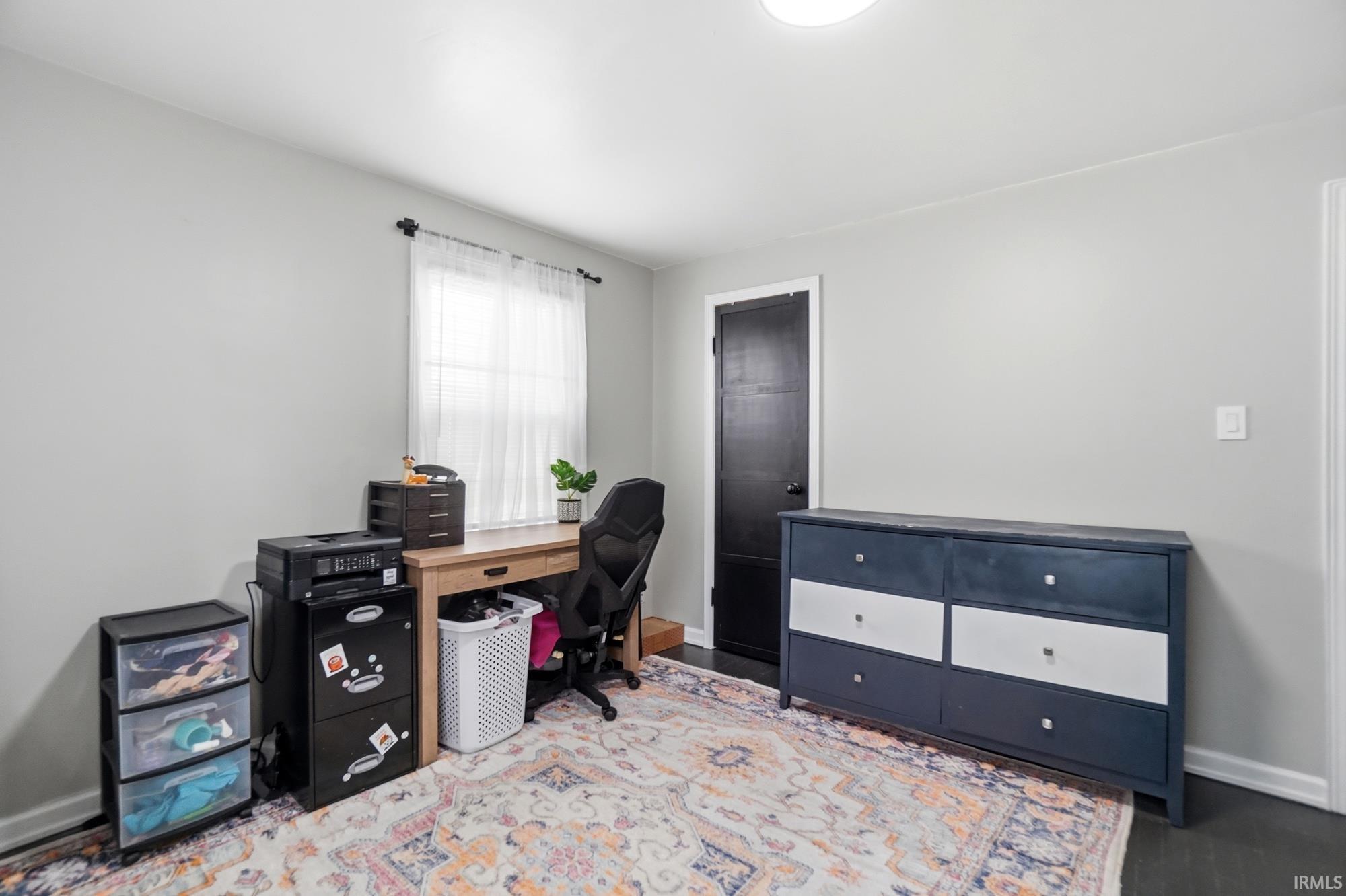 Bedroom featuring a window with natural light, light gray walls, dark wood-finish flooring, a flush-mount ceiling light, and white trim