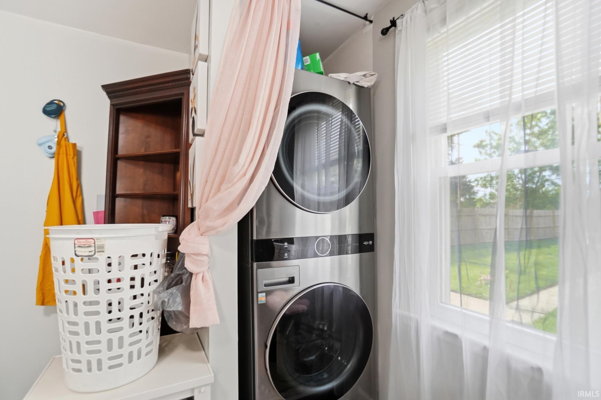 Stacked stainless steel laundry appliances with a side-by-side window offering exterior visibility