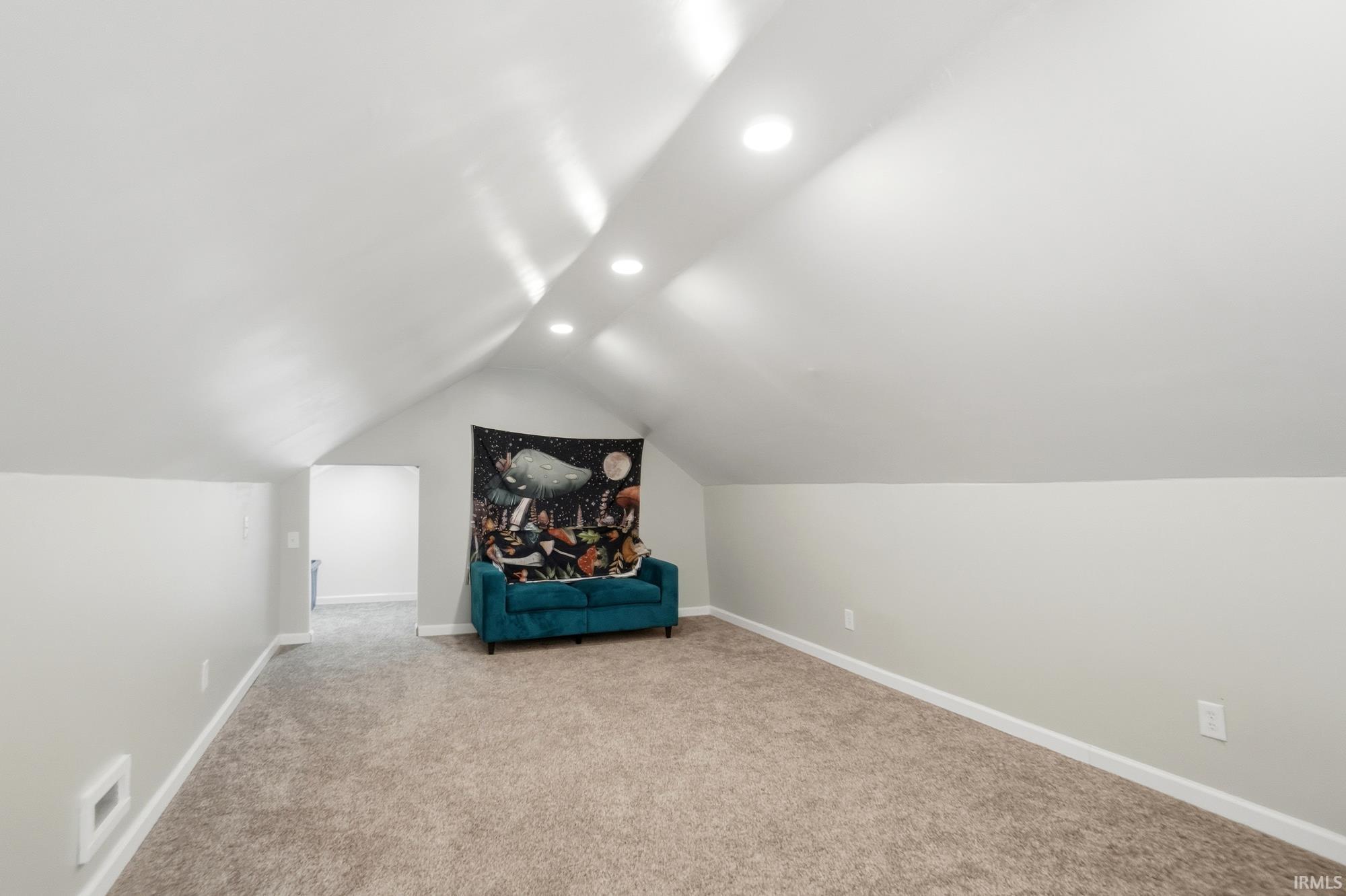 Carpeted room featuring a sloped ceiling with recessed lighting, light gray painted walls, white trim, and an open doorway