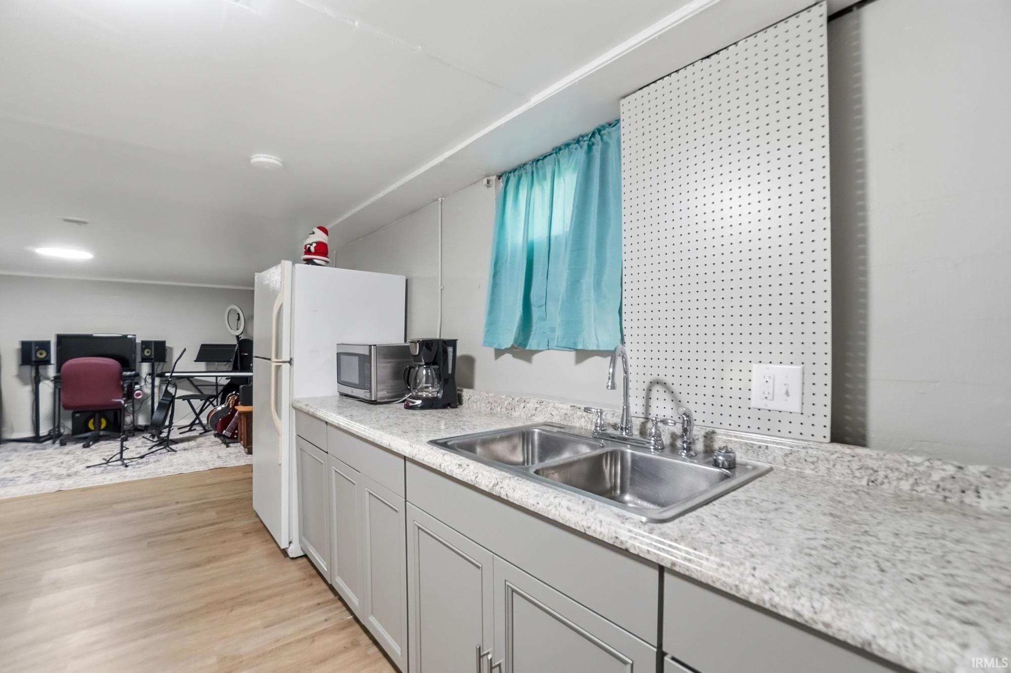 Kitchenette featuring light gray cabinetry, a double basin stainless steel sink, and light-toned mottled countertops