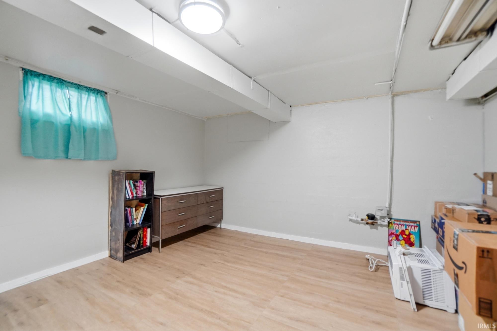 Versatile room featuring light wood-finish flooring, white walls, and a window with natural light