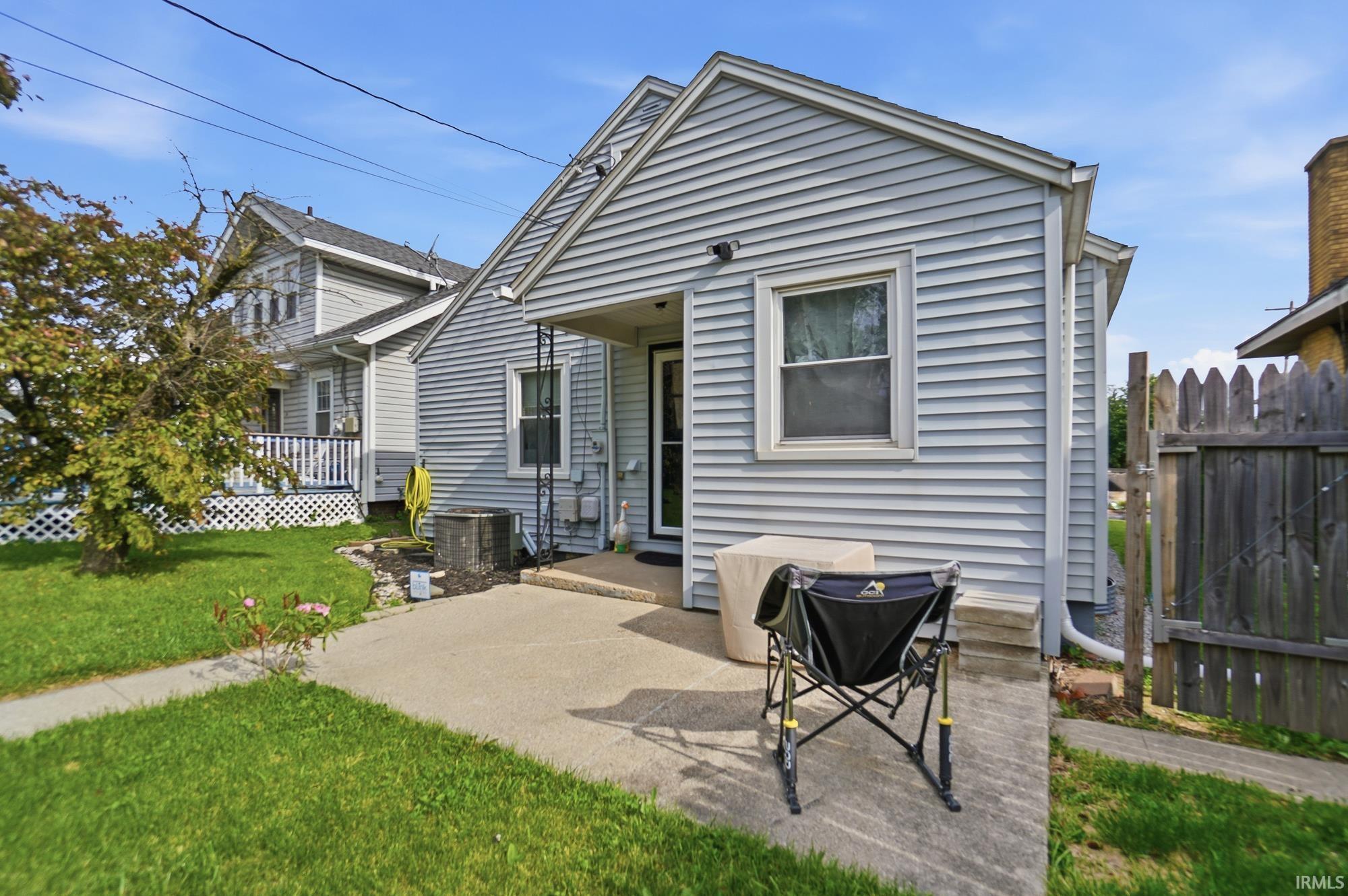 Rear exterior with light gray siding, featuring a concrete patio and a sloped concrete path
