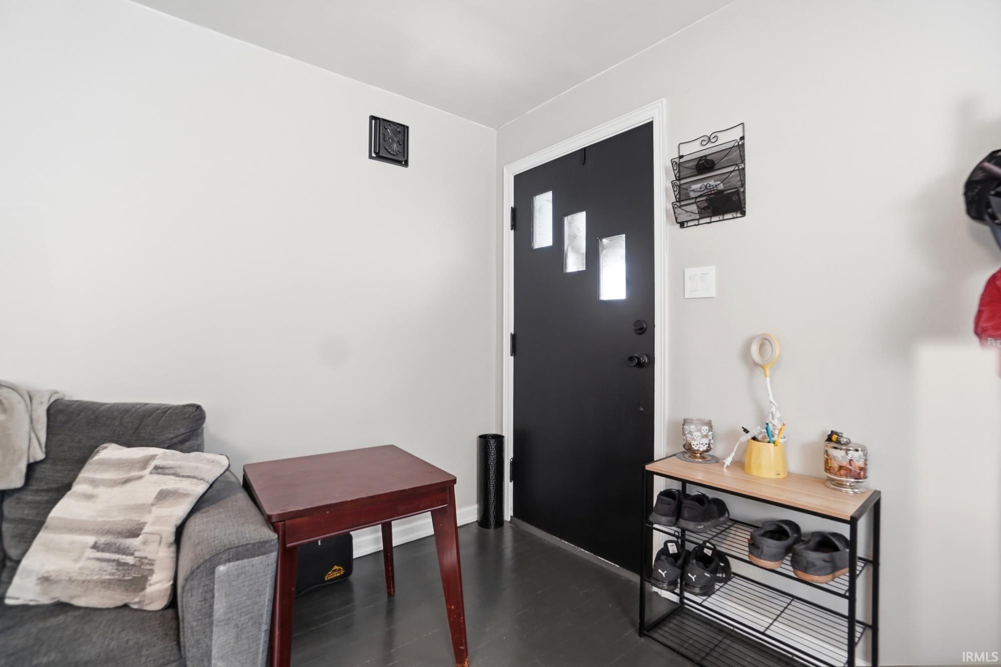 Black entry door with three rectangular frosted glass inserts, dark flooring, and light wall finishes