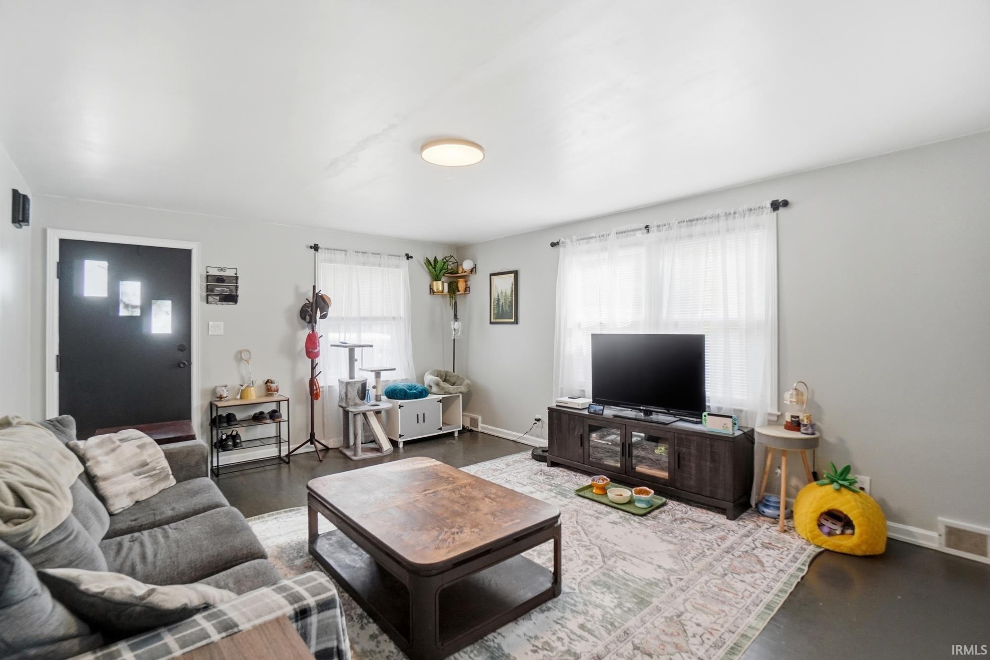 Living area featuring dark wood-finish flooring, light gray wall paint, and a front entry door with decorative glass inserts