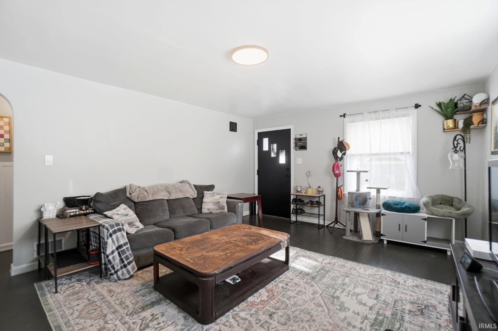 Bright living area featuring dark wood-finish flooring, light gray wall paint, and a white ceiling
