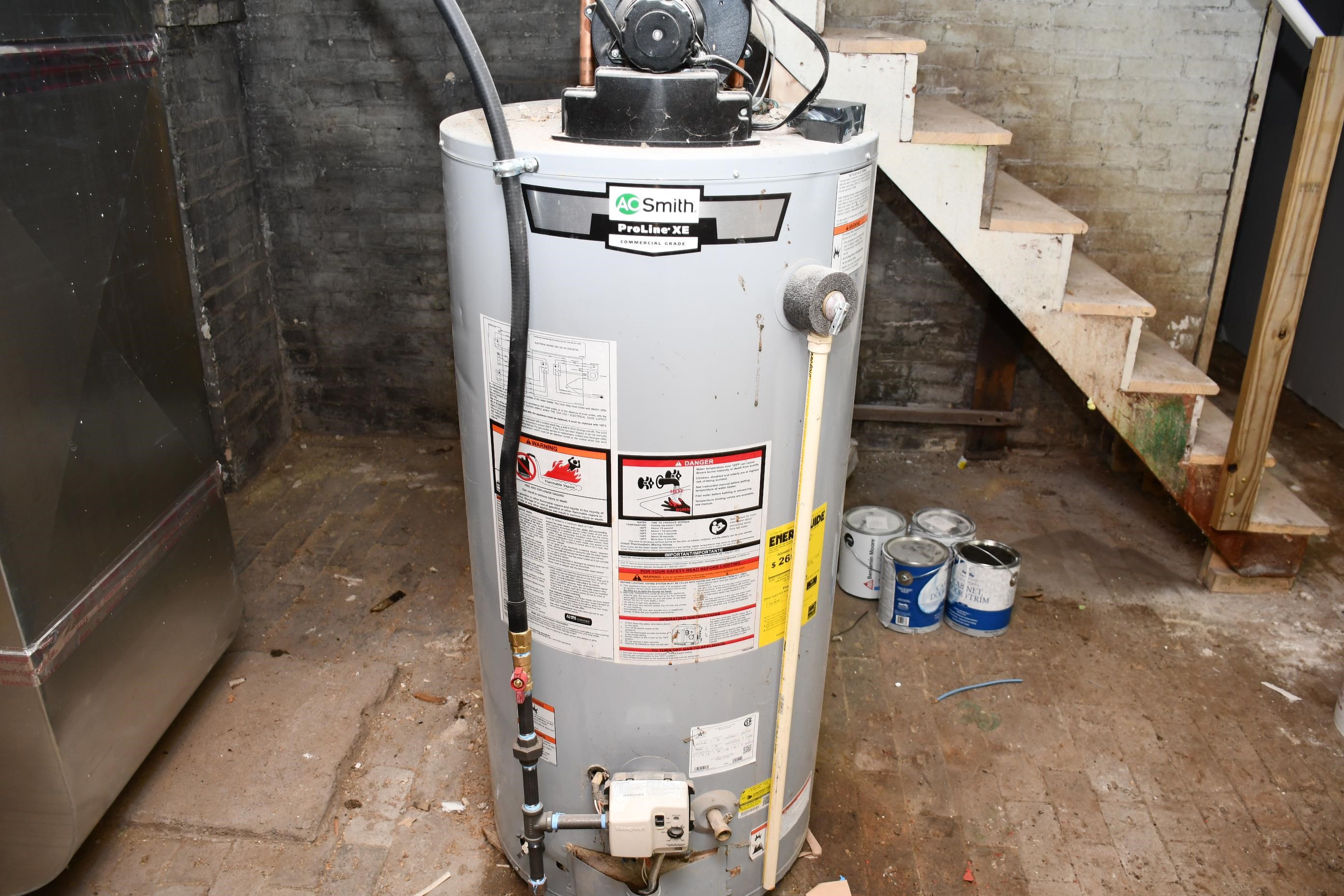 Smith ProLine XE water heater, visible ductwork, concrete flooring, and exposed brick walls