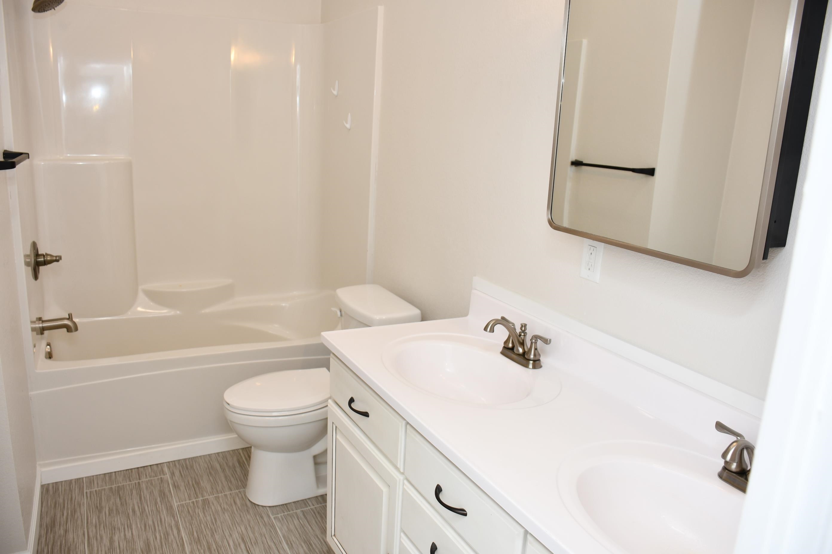 Dual vanity with integrated sinks, brushed nickel fixtures, white cabinetry, and a framed mirror