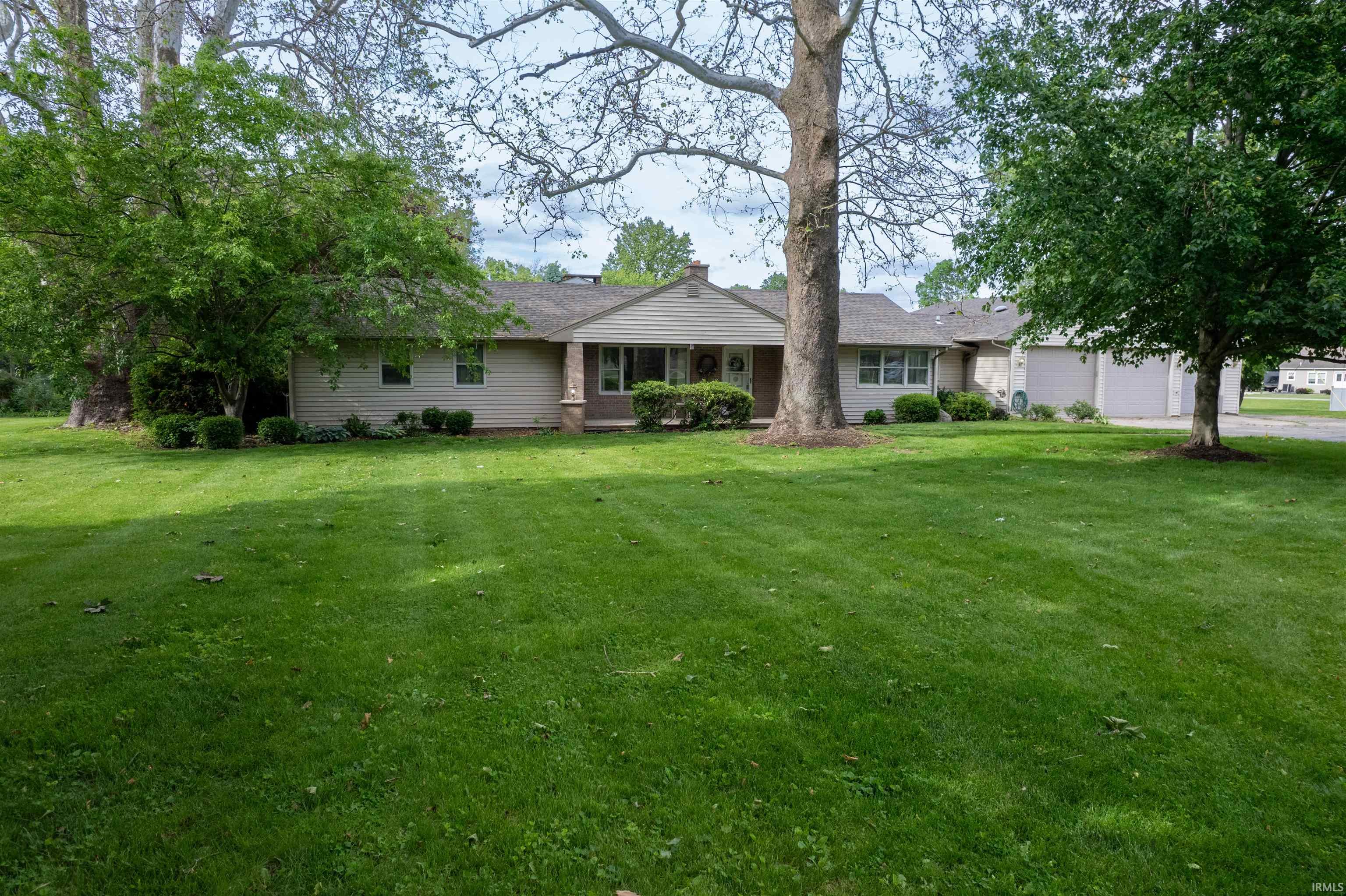 Ranch-style residence featuring light-colored siding, a covered entry porch with structural columns, and a multi-car garage