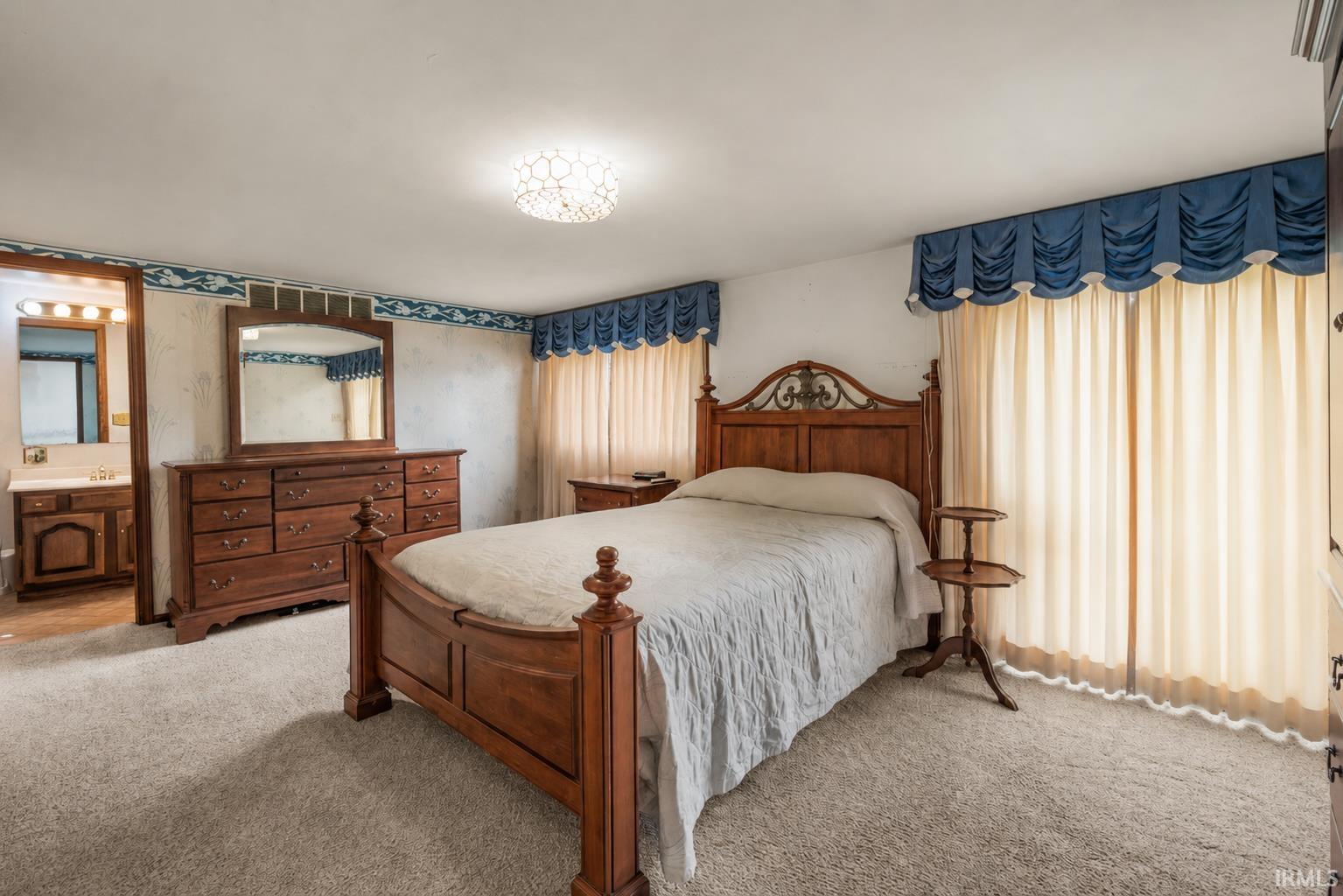 Carpeted room featuring a ceiling-mounted light fixture, decorative wall border, and a broad window opening