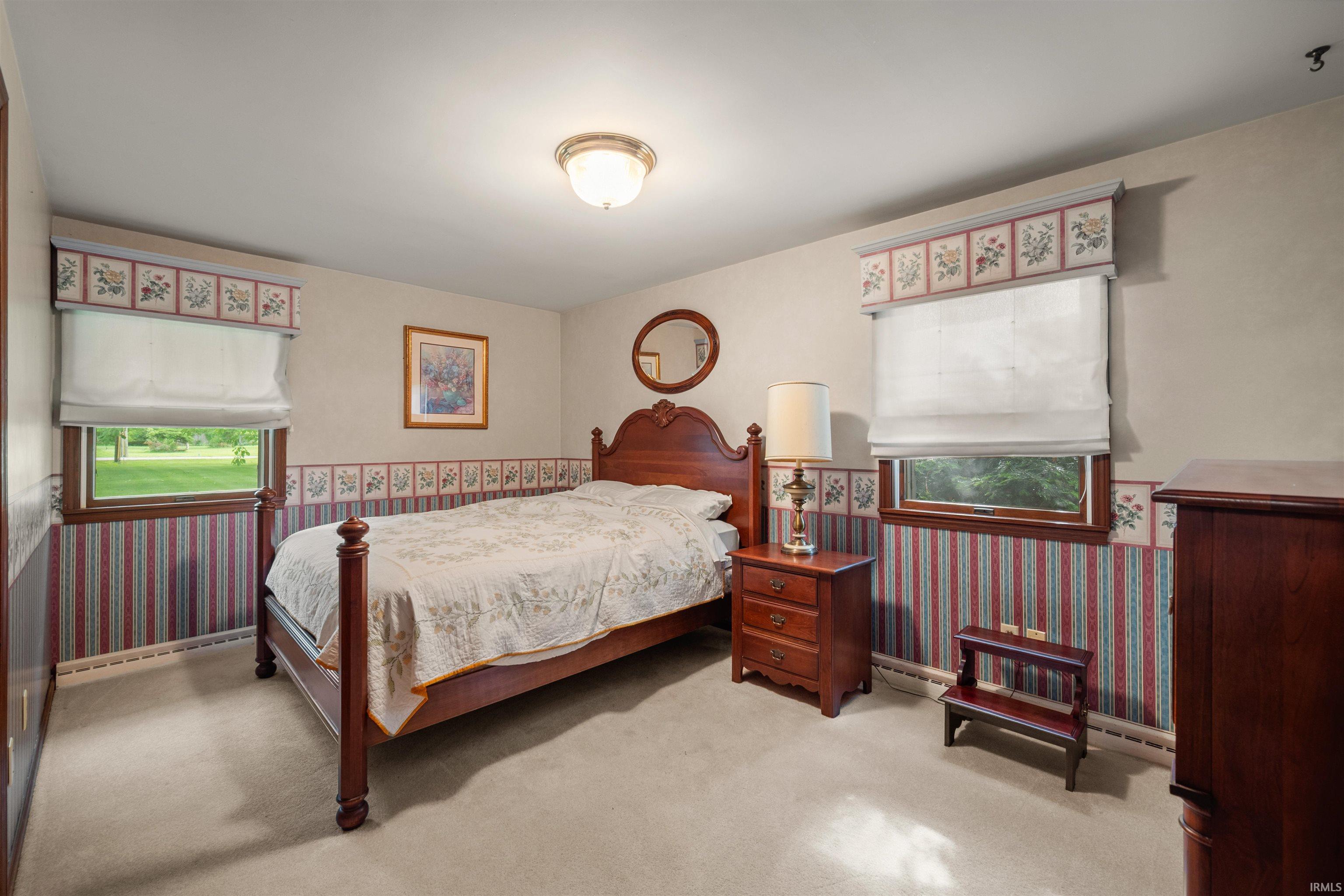Carpeted room with a central ceiling light fixture and two windows featuring window treatments