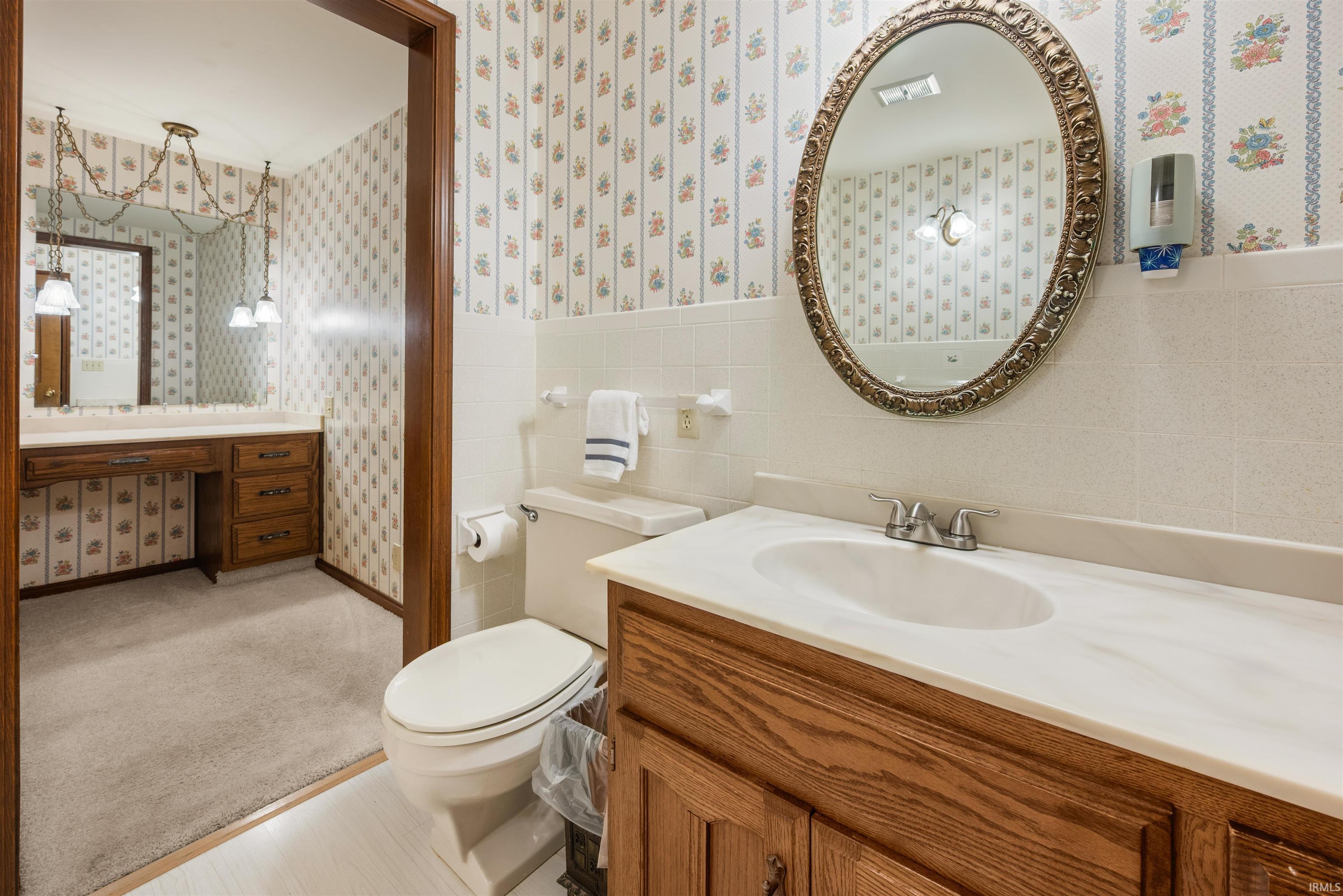 Bathroom featuring a wood-finish vanity with a built-in sink and a decorative oval mirror
