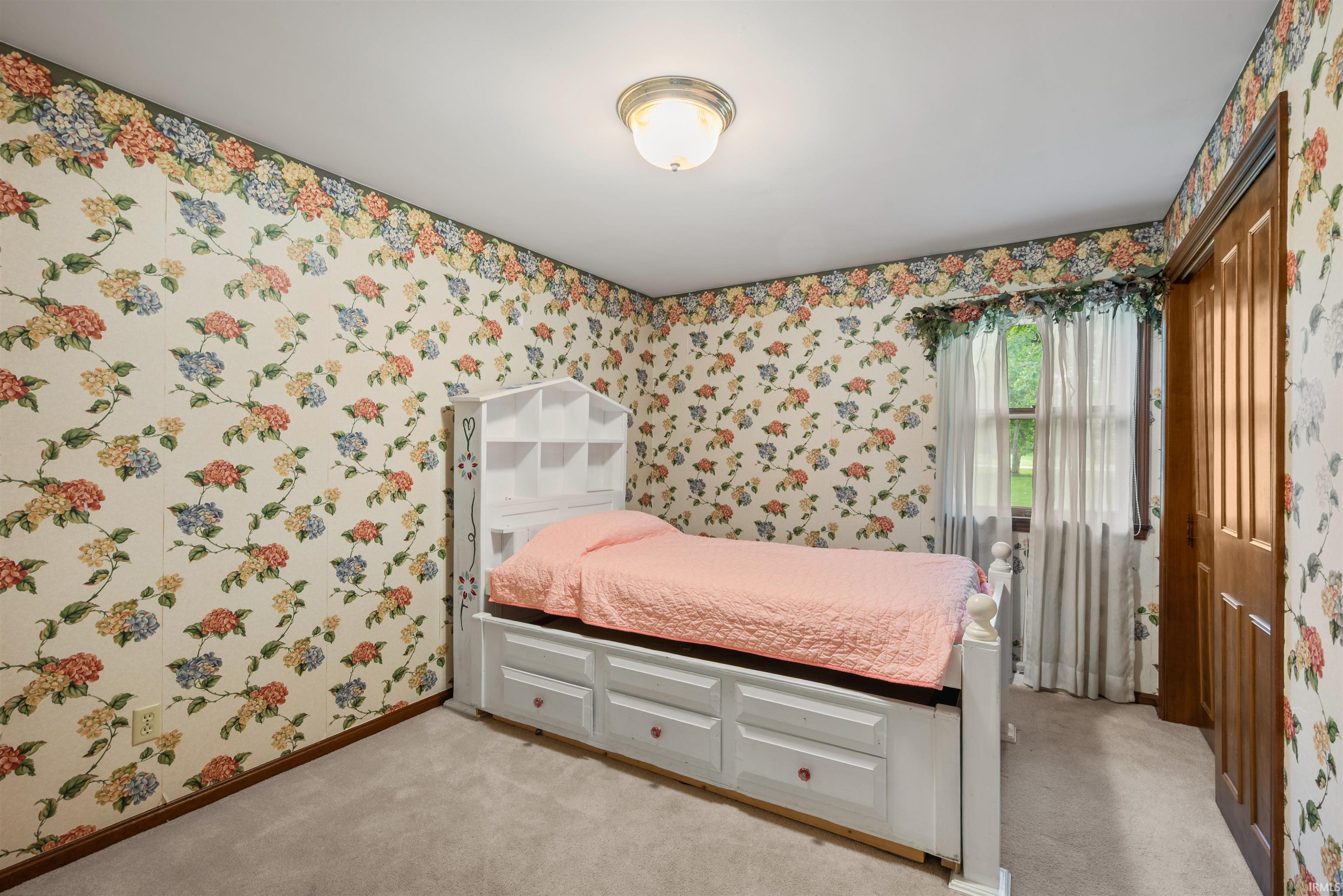 Carpeted room with floral wallpaper and a ceiling-mounted light fixture