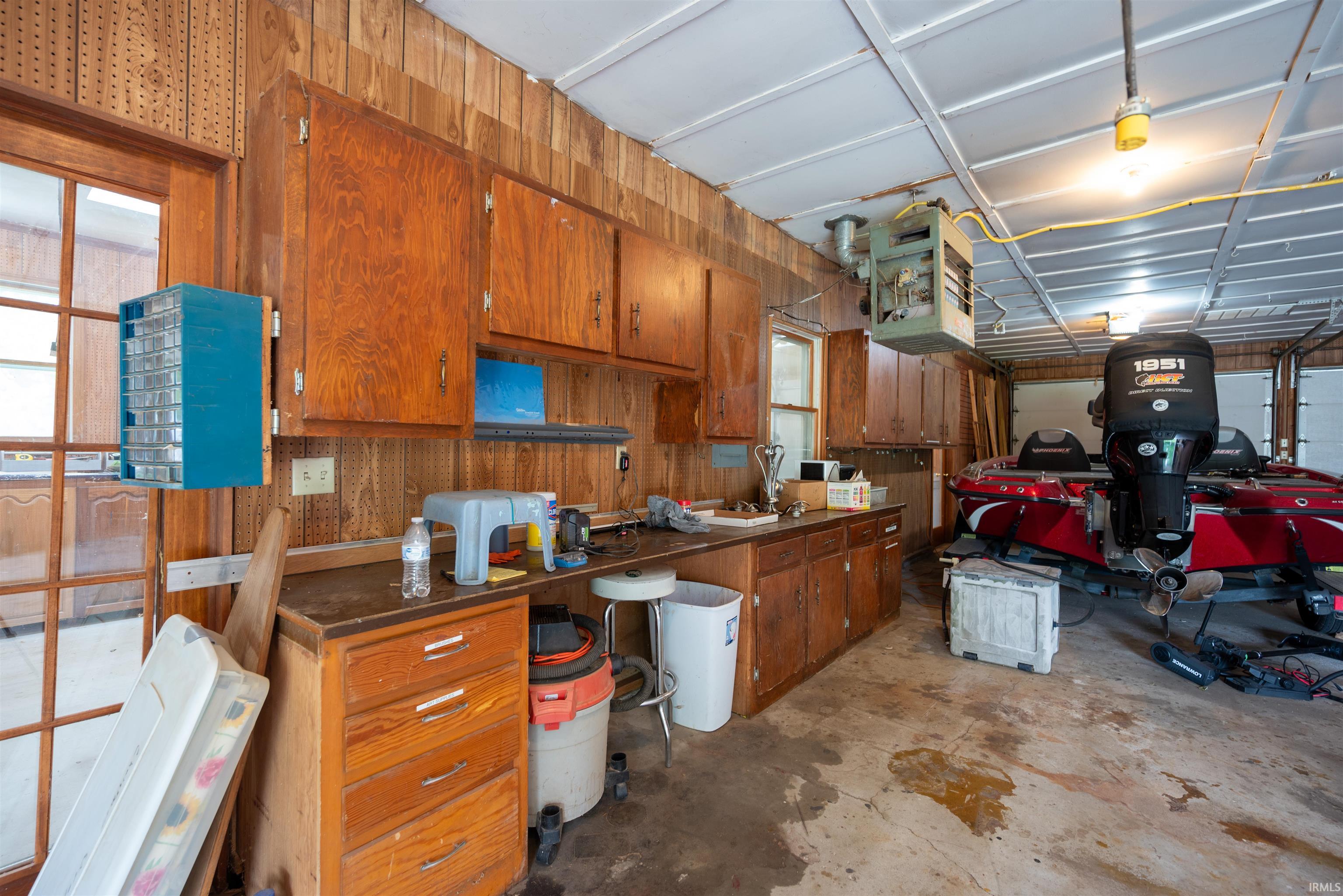 Garage workspace featuring wood paneling, built-in cabinetry, an overhead light fixture, and a window with wood-frame glass panes