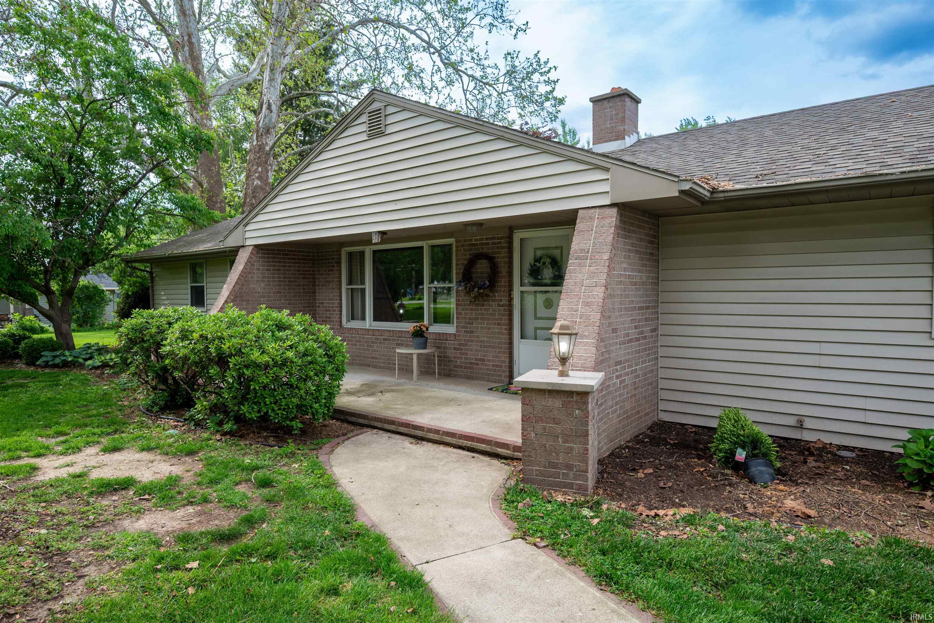 Single-story residence featuring a brick and siding exterior, a gabled roofline, and mature landscaping