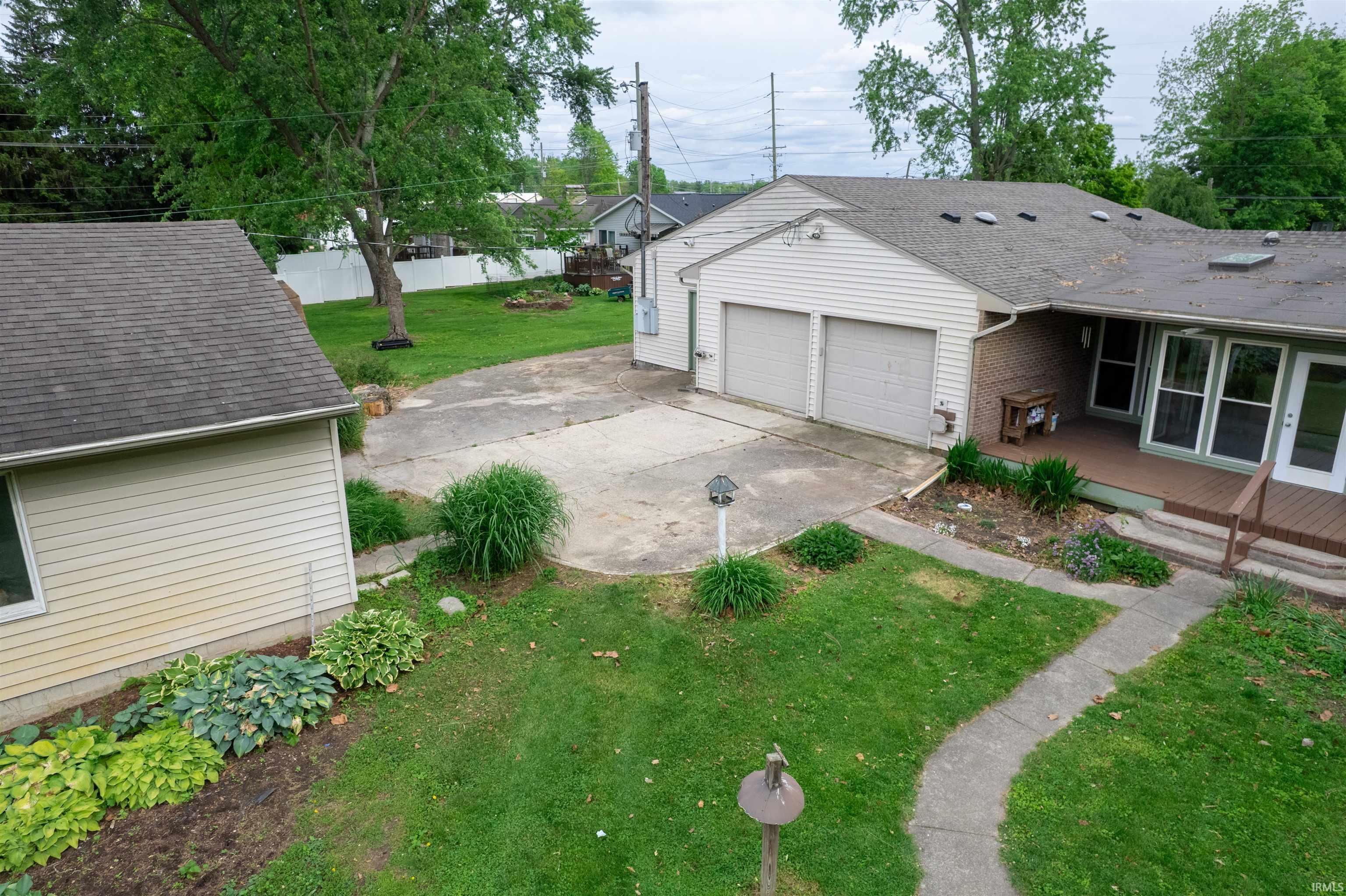 Exterior featuring a two-car garage, concrete driveway, and a wood-finish deck