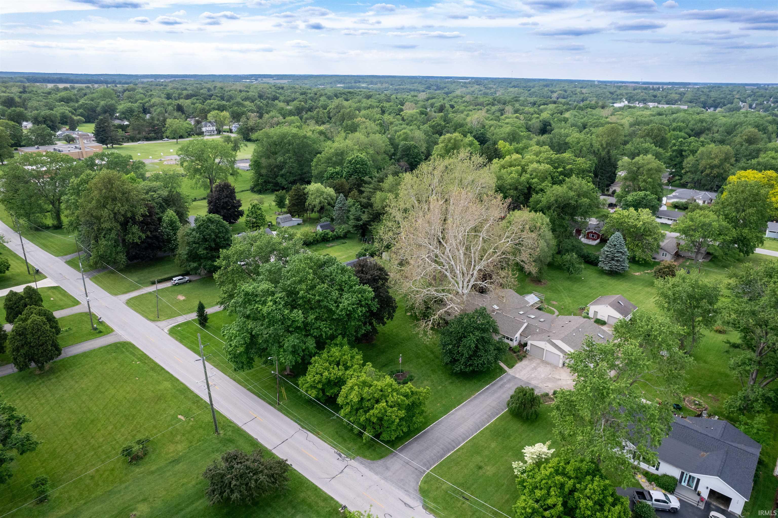 Expansive property featuring a single-story residence with an attached garage, a detached garage, and a long asphalt driveway